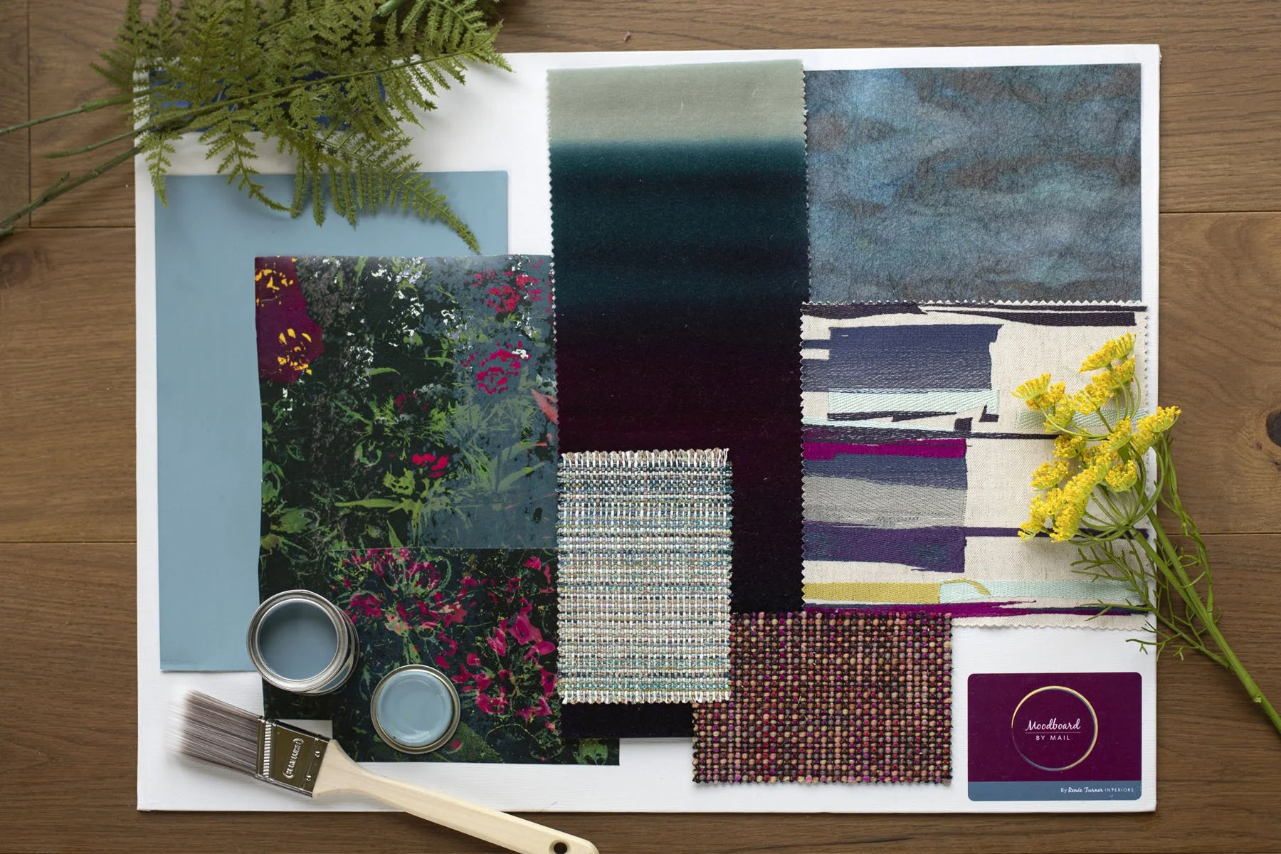Interior design mood board with fabric swatches, paint samples, floral prints, and decorative elements on a white board.