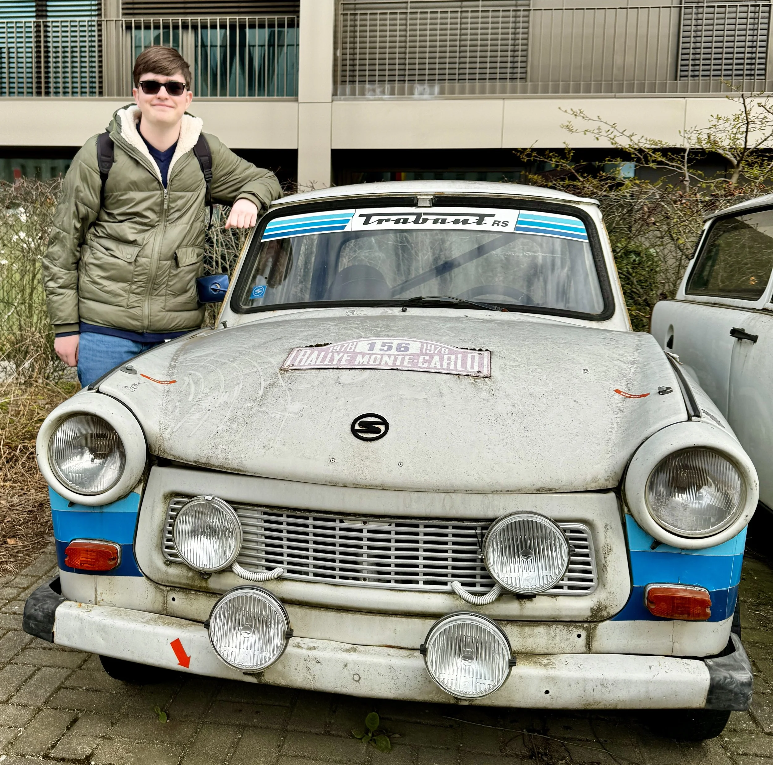 Teen standing next to a vintage Trabant car during a Berlin Trabi tour