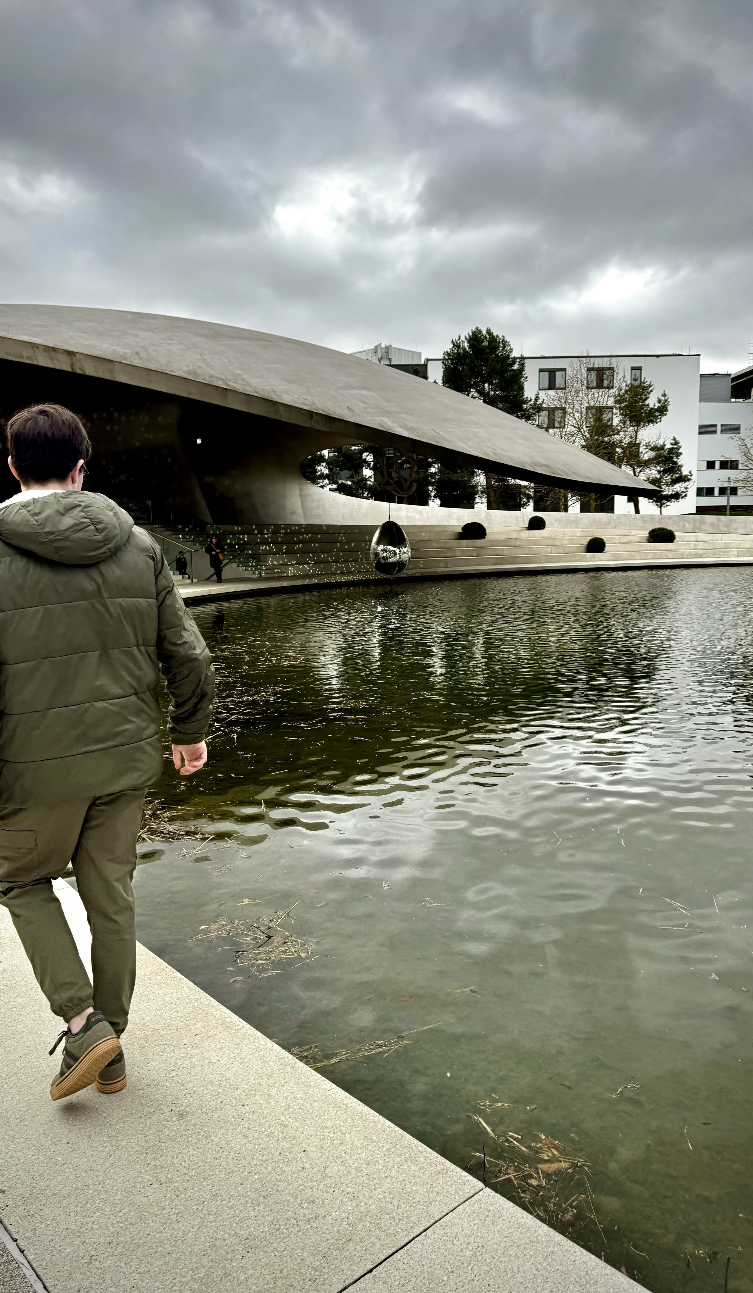 Exterior view of the Porsche pavilion at Autostadt with a teen in the foreground.