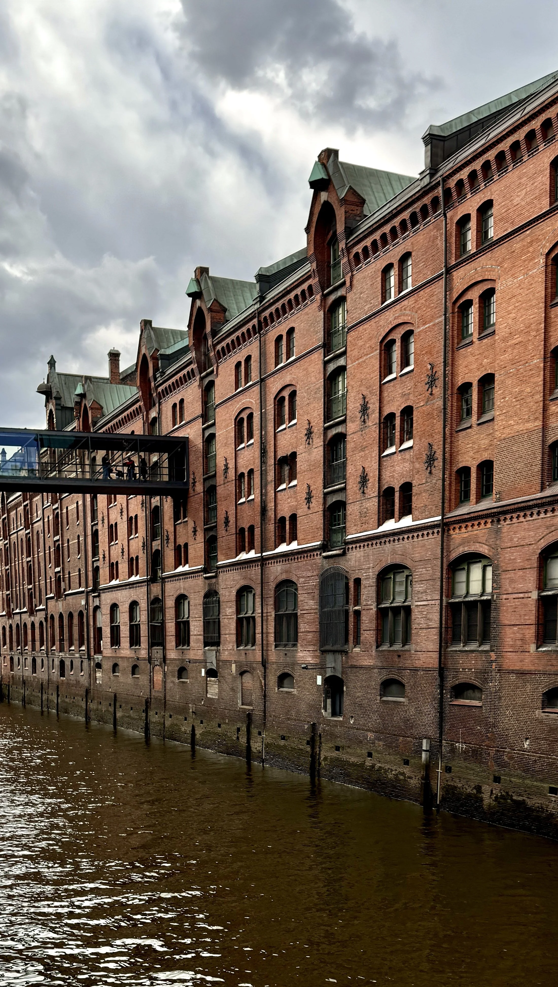 Exterior view of Miniatur Wunderland in Hamburg’s historic Speicherstadt warehouse district with visitors walking across a skybridge.