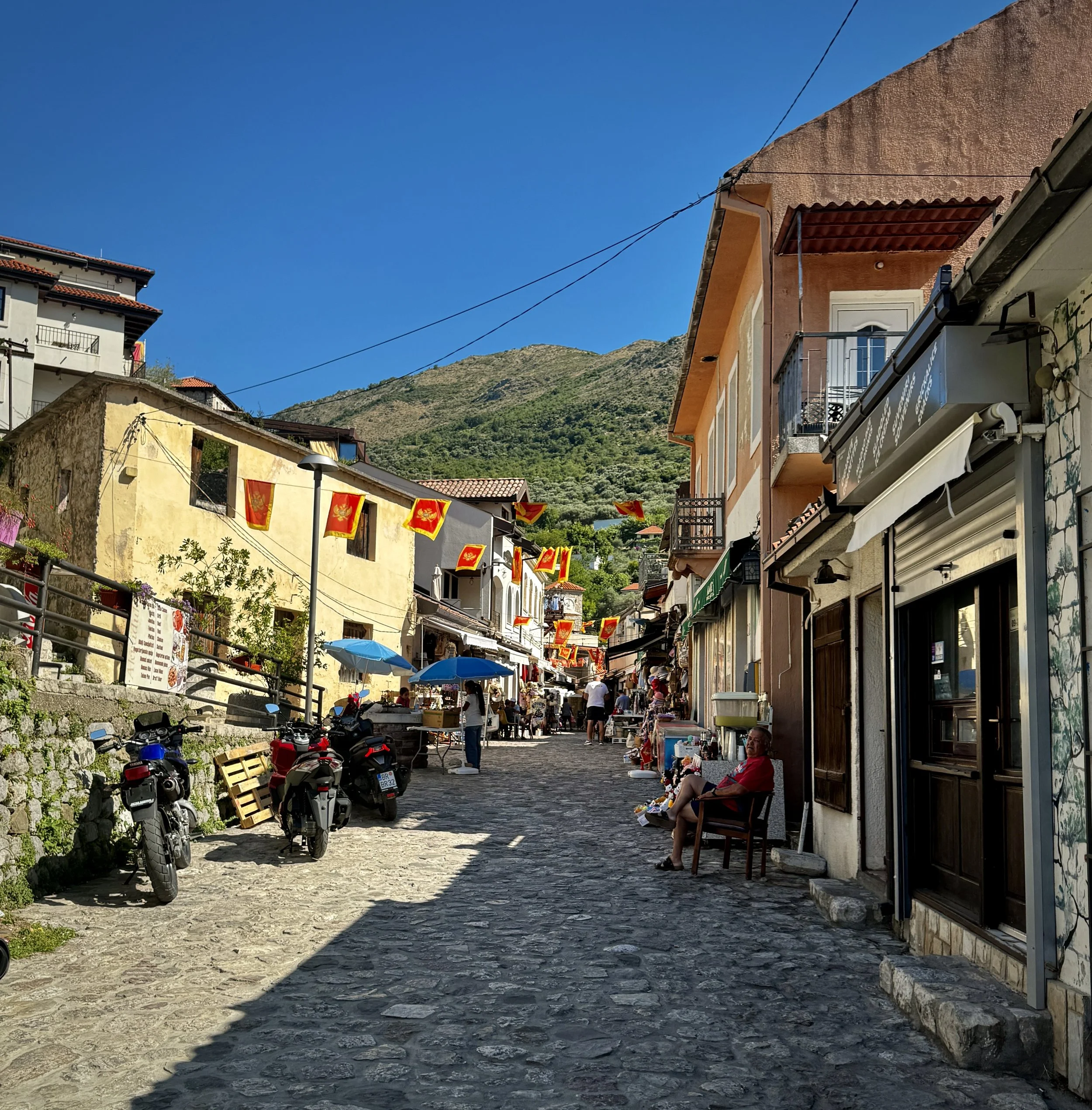 Cobblestone street lined with shops and cafes leading toward Stari Bar in Montenegro.