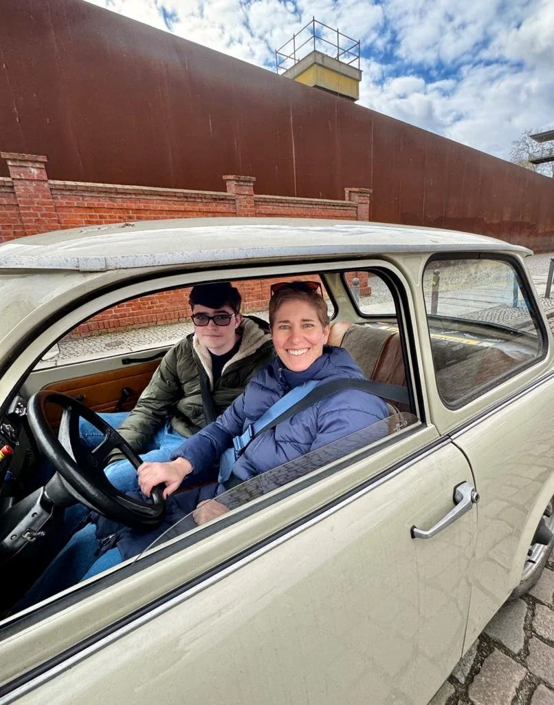 Family driving a Trabant during a Berlin Trabi tour experience.