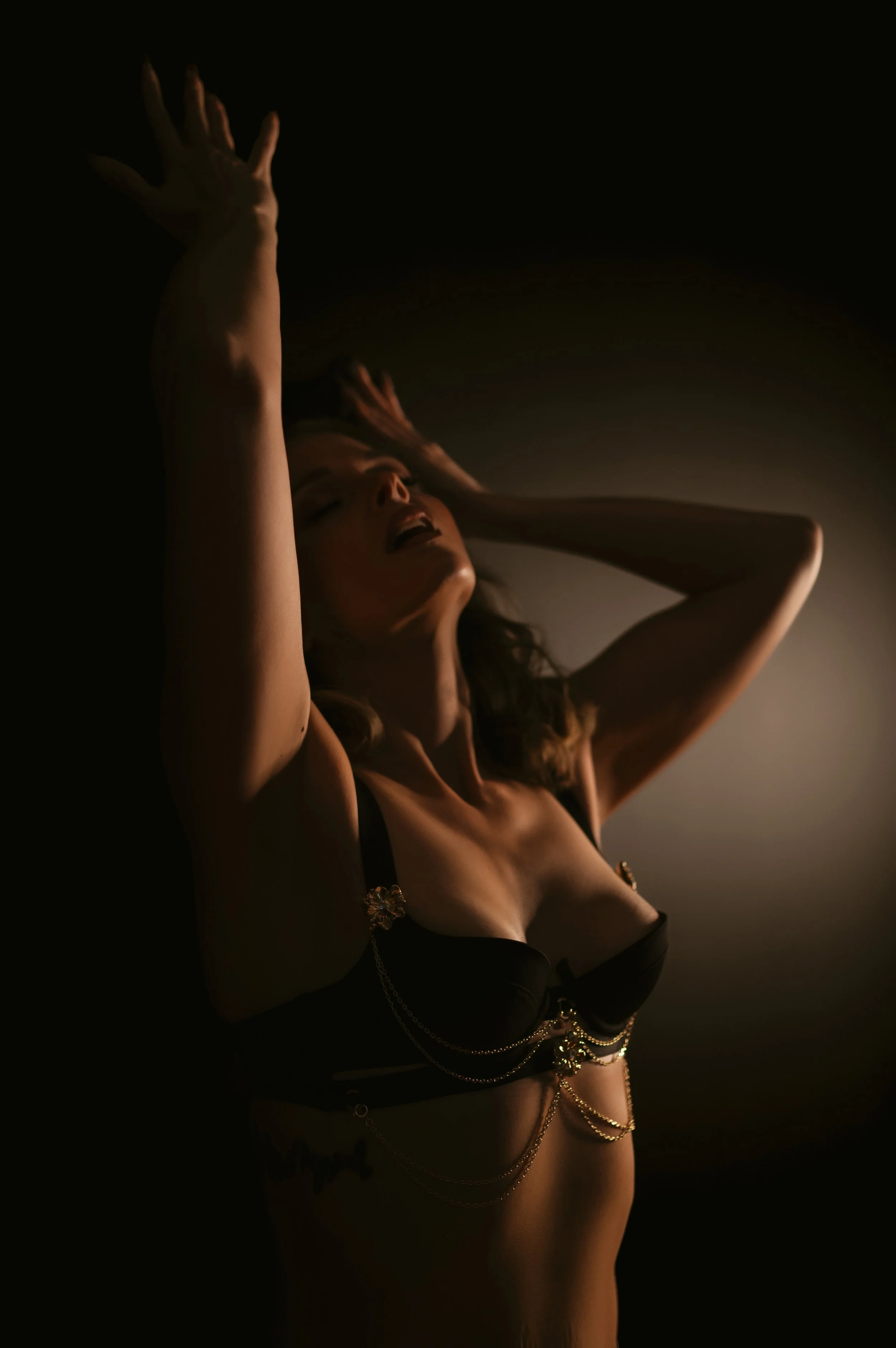 woman in black and gold lingerie against black wall
