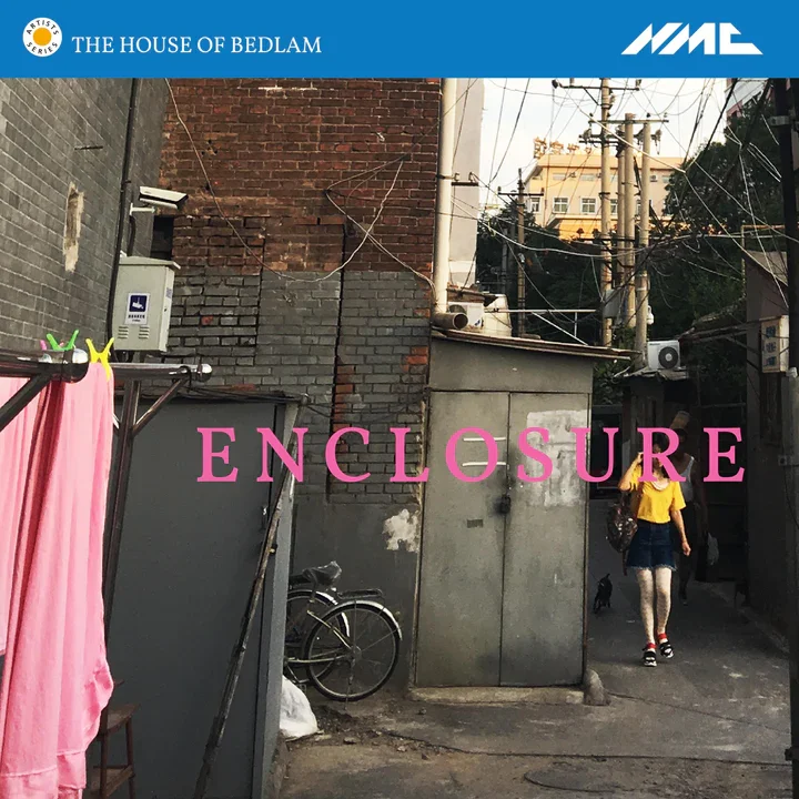 An alleyway in an urban area with utility wires overhead, a bicycle leaned against a wall, and a person walking away wearing a yellow shirt and skirt. There is a pink cloth hanging on a clothesline, and the focus is on a metal structure with the word
