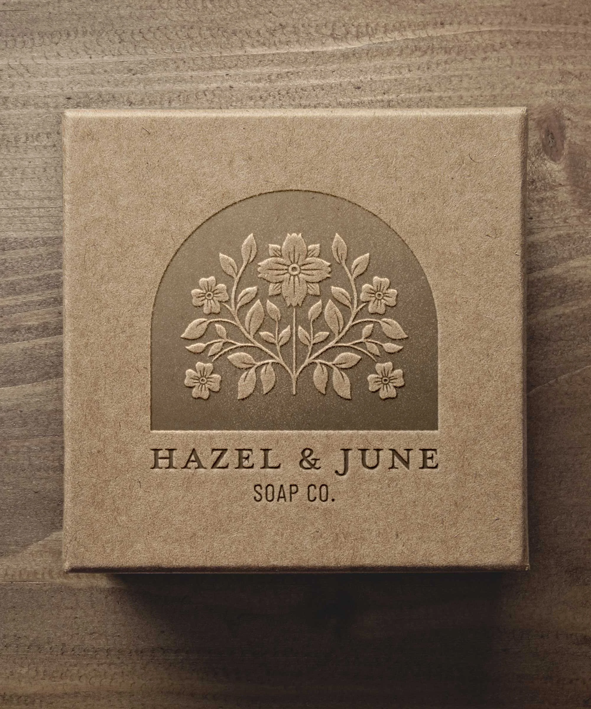A beige box with an embossed floral design and the text 'Hazel & June Soap Co.' underneath.
