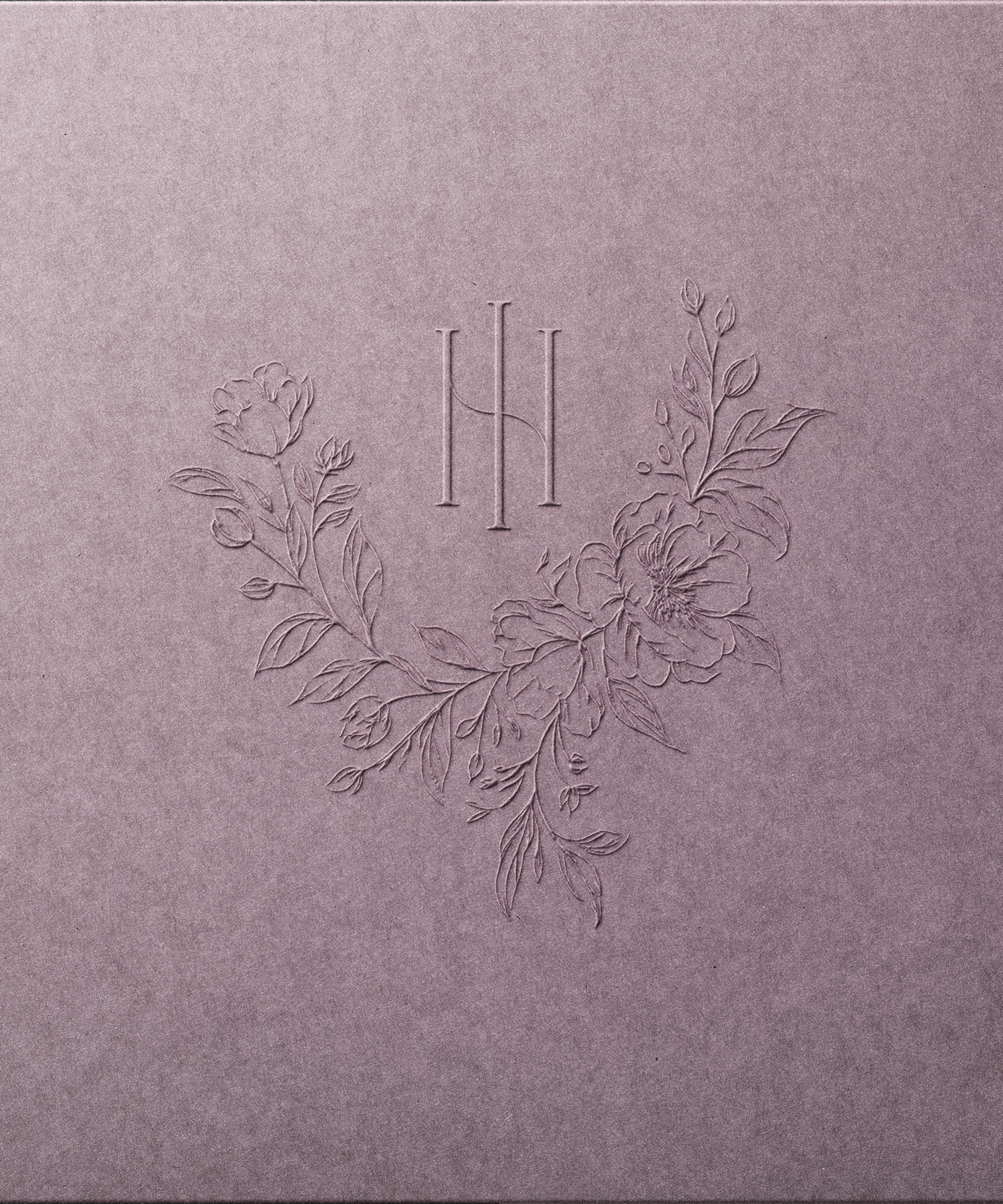 Purple textured paper with embossed floral design and a monogrammed letter 'H' in the center.