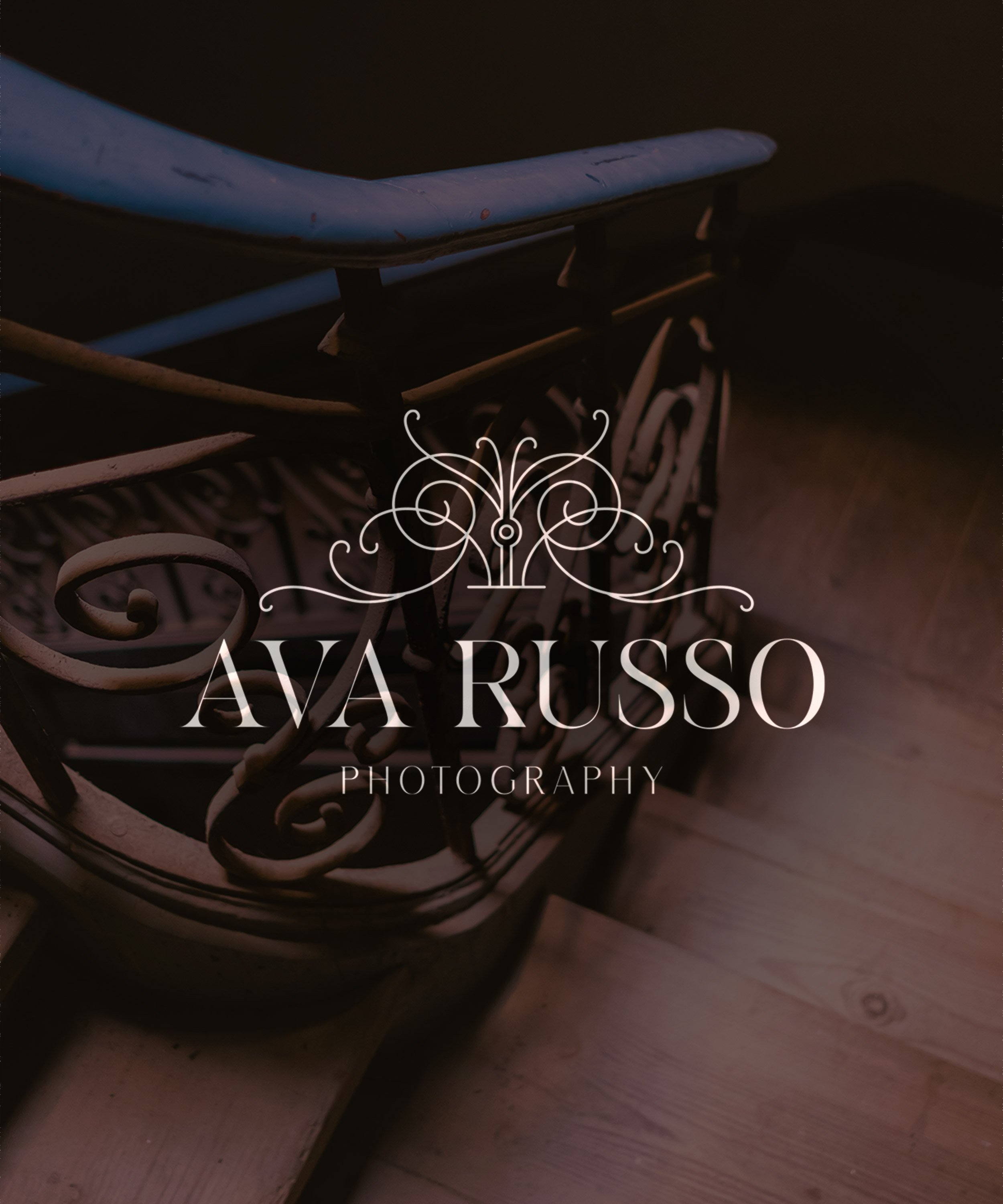 Close-up of vintage wooden and metal staircase handrail with ornate ironwork, and a dark background.