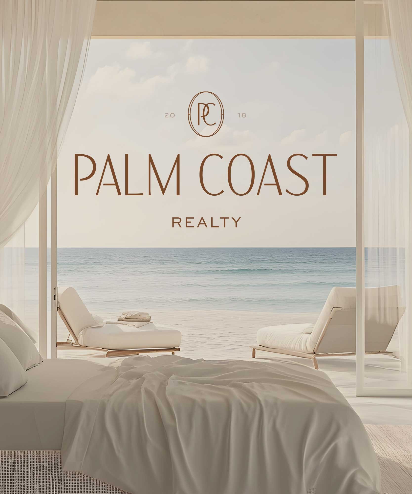 Beachside view through large glass door, with a bed in the foreground and two lounge chairs outside on the sand, advertising Palm Coast Realty.