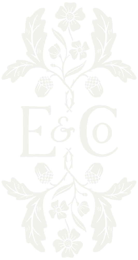 A black and white floral logo with a symmetrical design featuring leaves and flowers above and below the central text 'E & Co'.