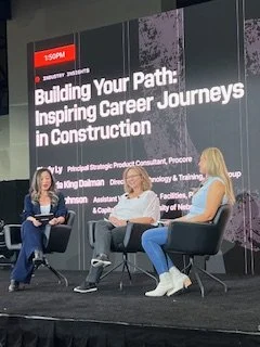 Panel discussion on construction careers, with three people seated on stage in front of a large screen that reads 'Building Your Path: Inspiring Career Journeys in Construction'.
