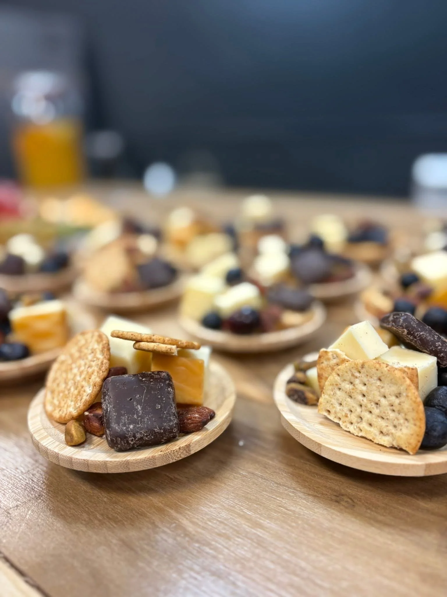 Variety of cheese and chocolate pieces on small wooden plates on a table.