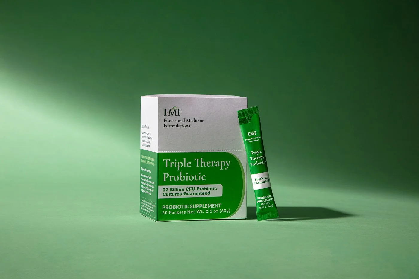Box of Triple Therapy Probiotic supplement with a single packet in front against a green background.