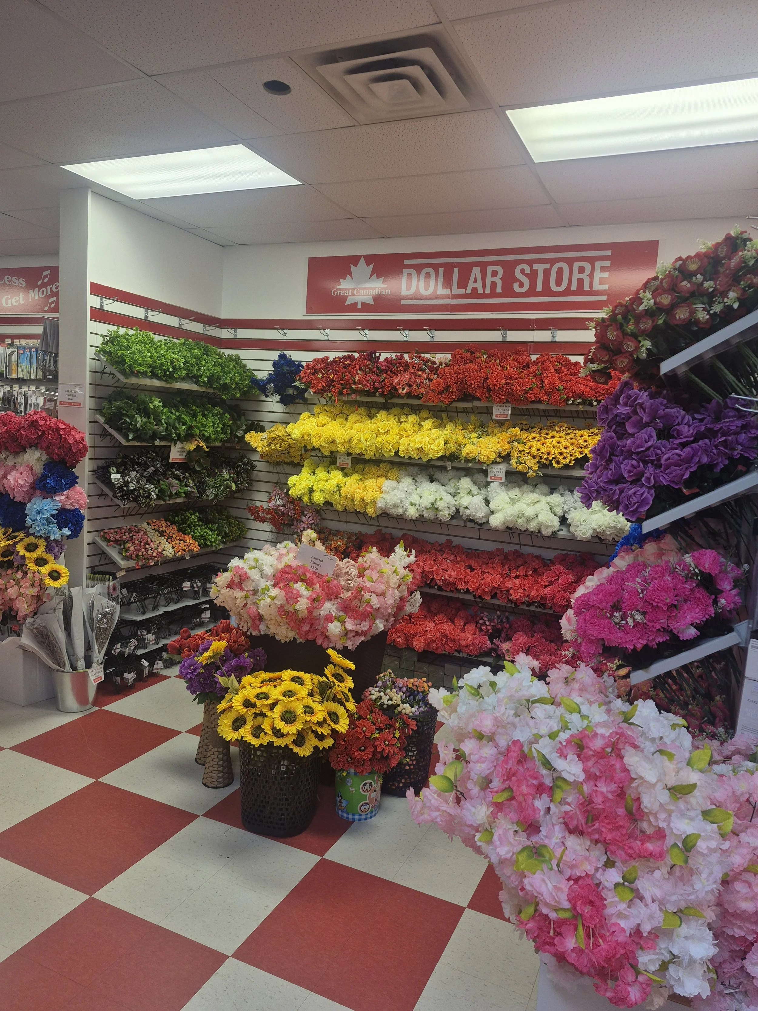 Display of various colorful artificial flowers at a dollar store with a sign reading 'Great Canadian Dollar Store'