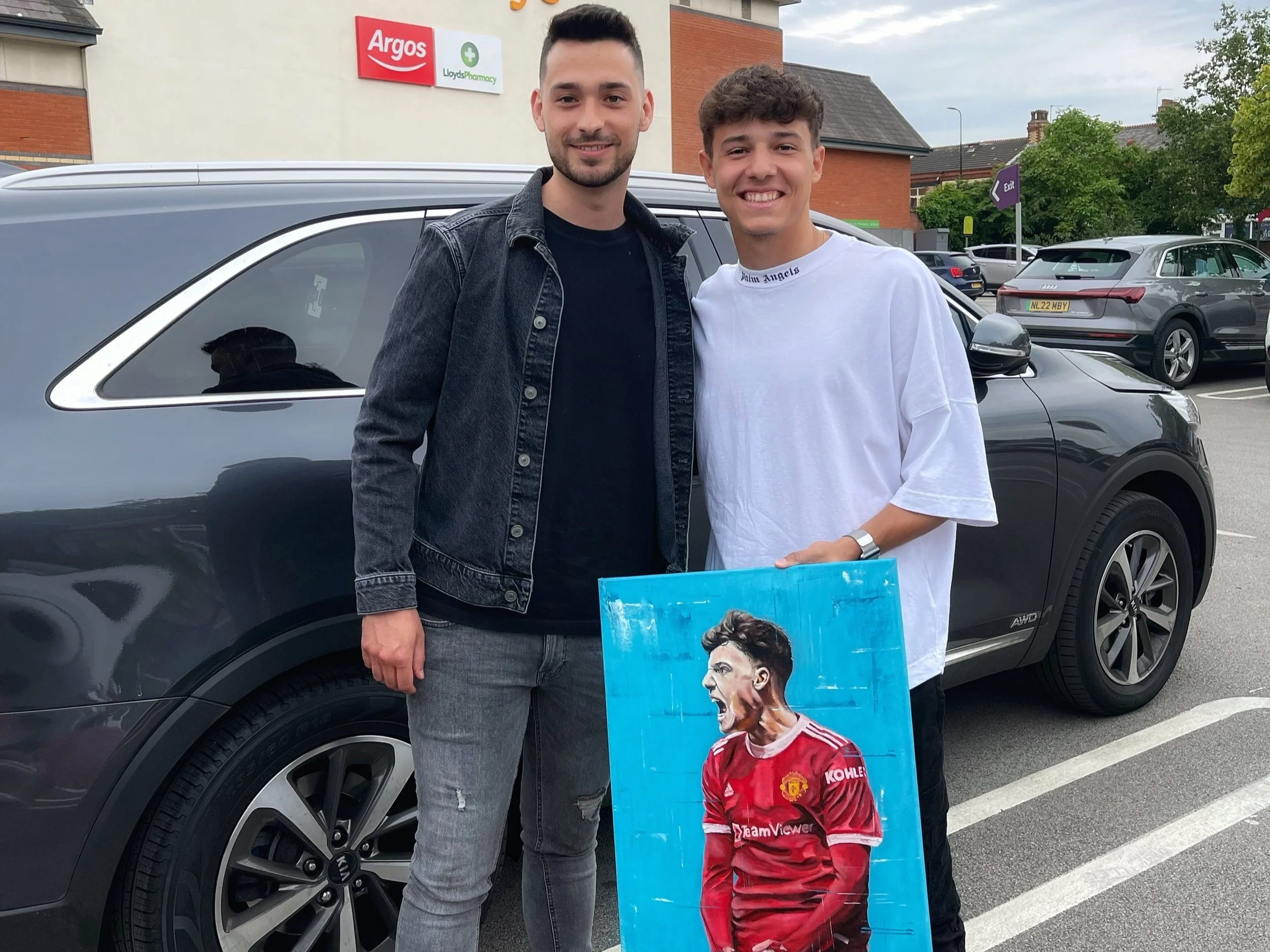 two people smiling with one holding a portrait