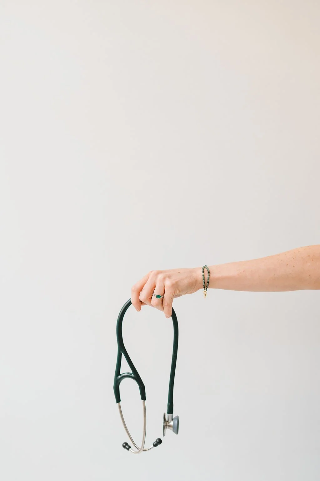 A minimal, clean image of a hand holding a stethoscope against a soft neutral background, symbolizing care, connection, and a personal approach to healthcare.