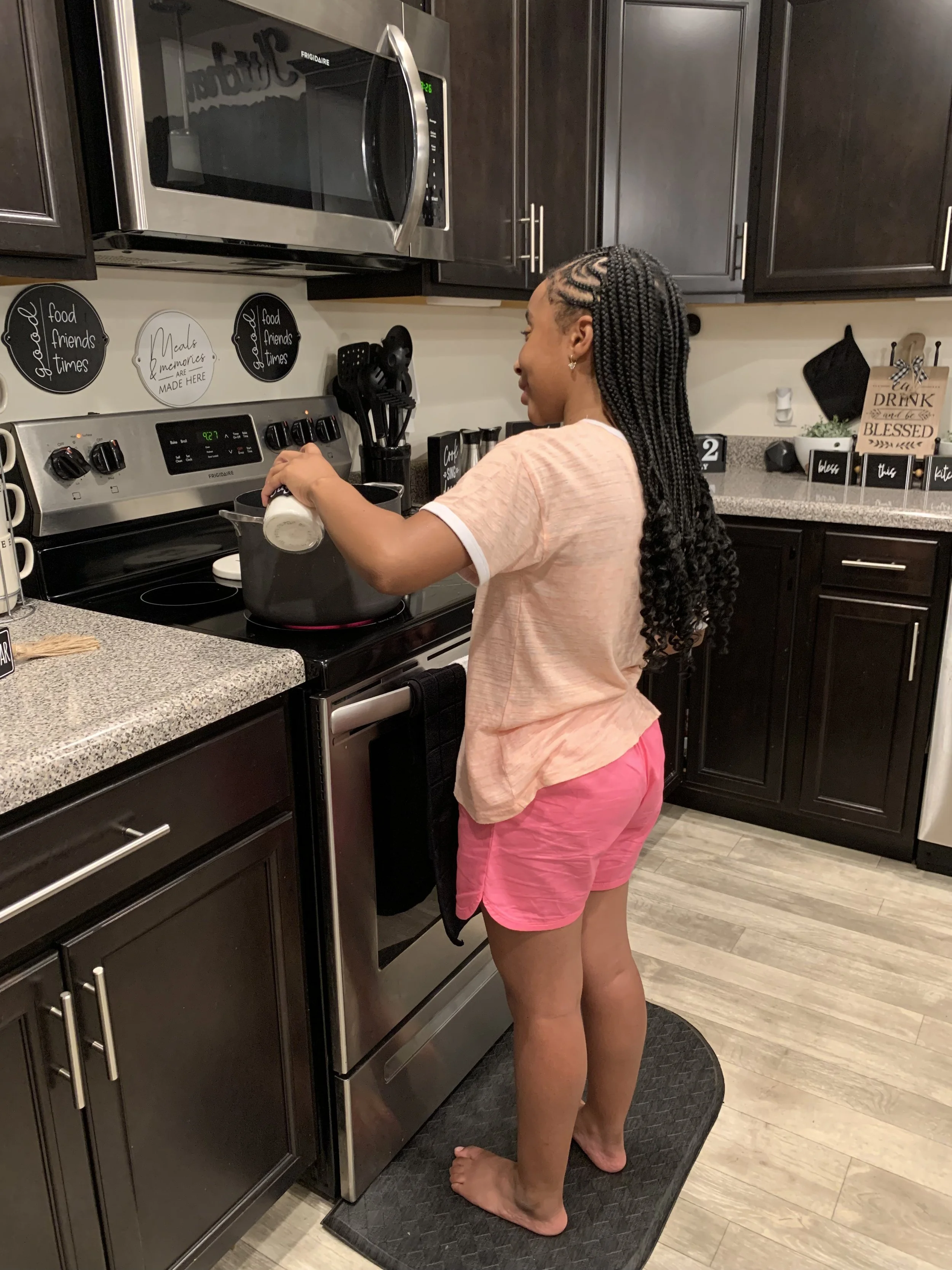 A young girl with braided hair cooking on a stove in a modern kitchen. Providing flavorfull homemade lemonade to your doorstep.