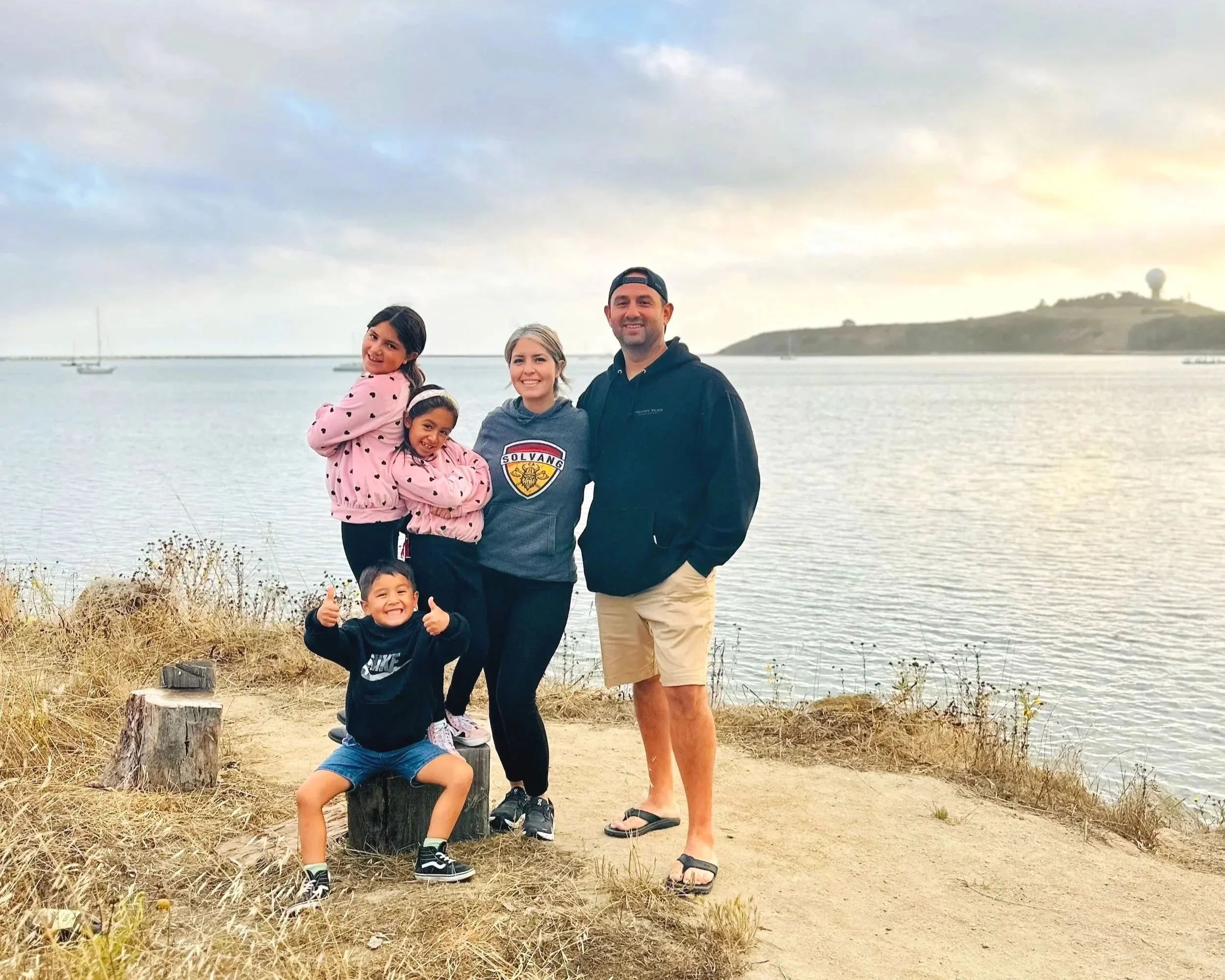Darlene with her husband and three children standing together by the water.