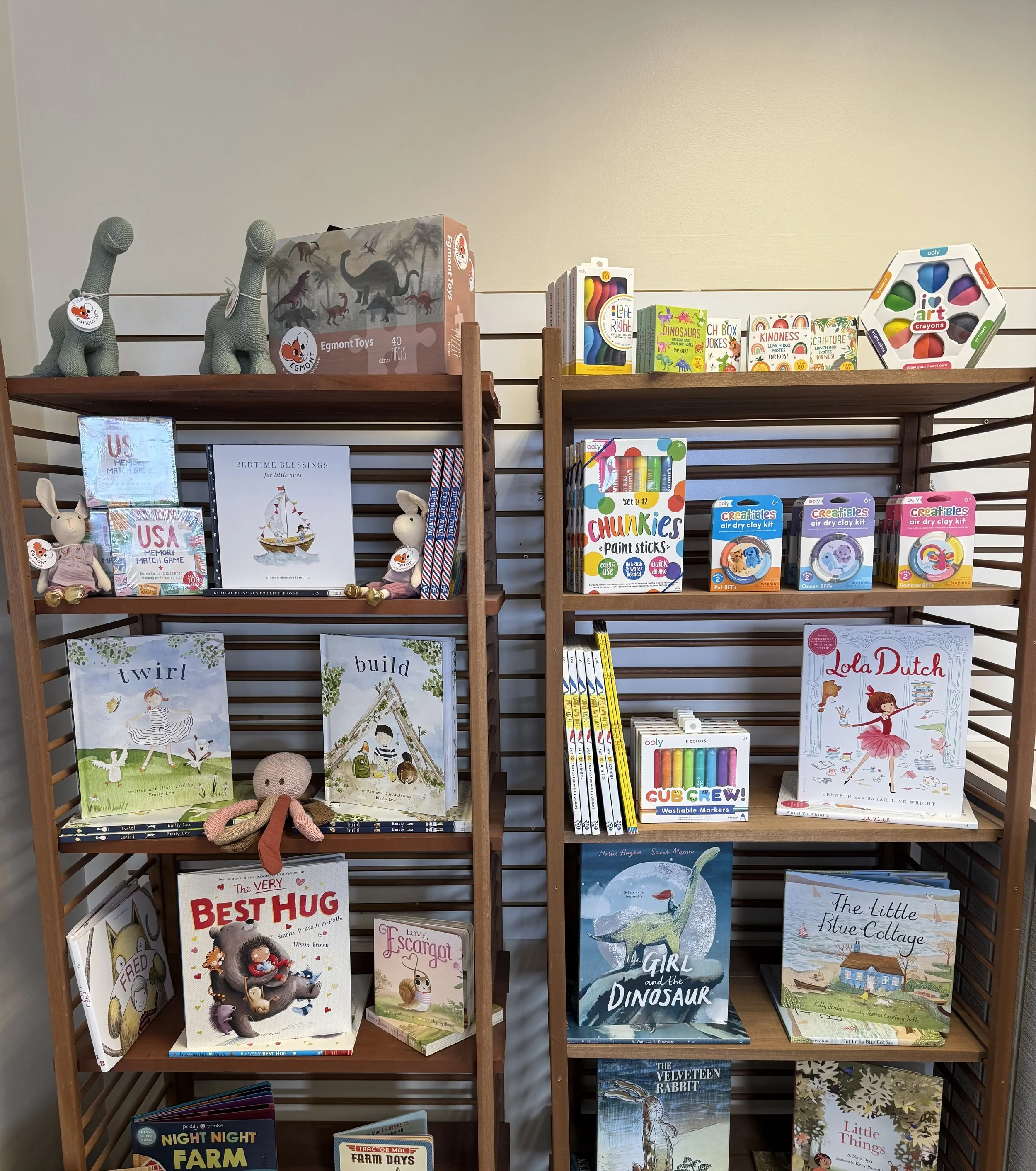 Books, toys, and art supplies on two wooden shelves in a bookstore or library.