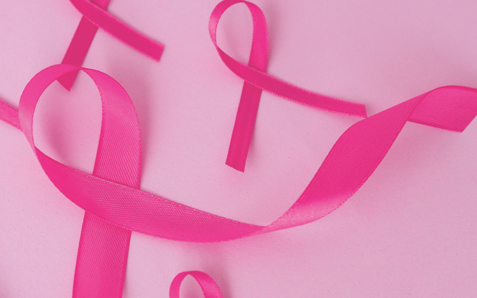 Pink ribbon hearts on a pink background, symbolizing breast cancer awareness.