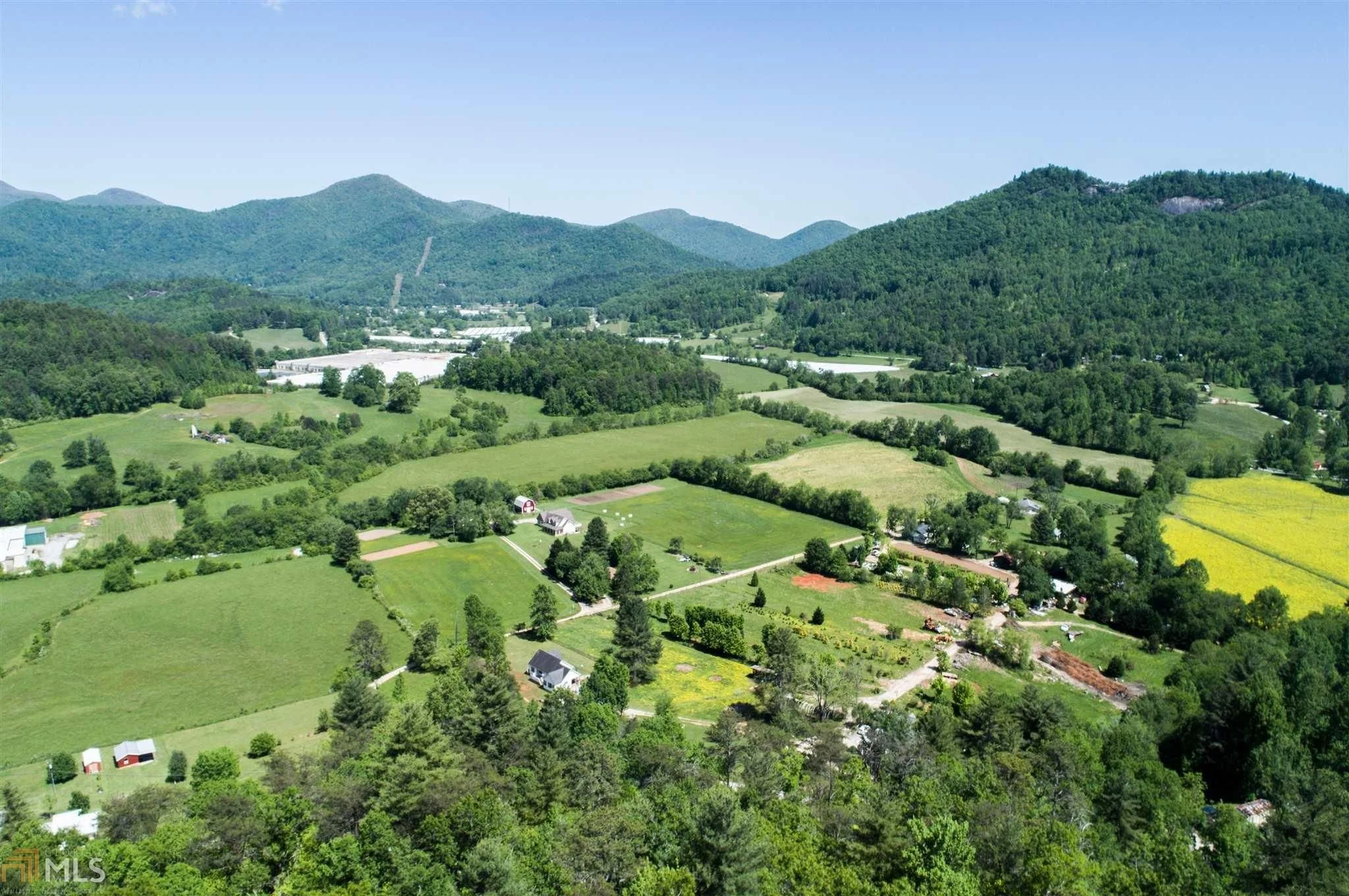 Aerial view of green farmland, forests, and mountains during daytime.