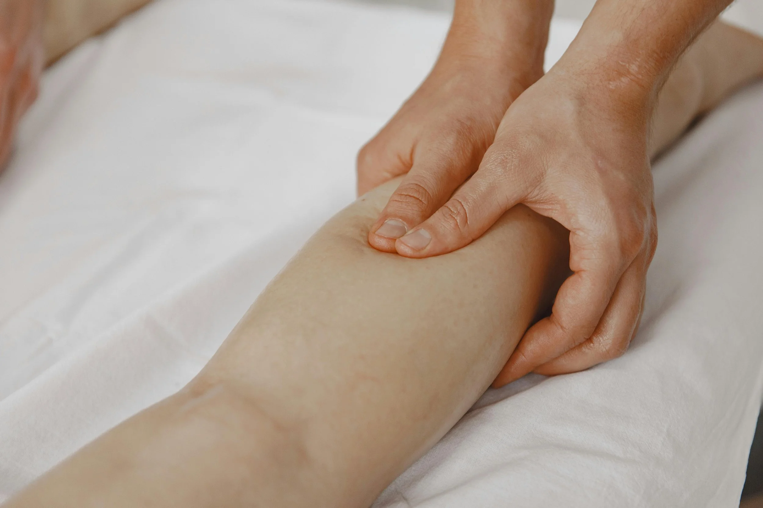 Person receiving a massage on their leg from a massage therapist.