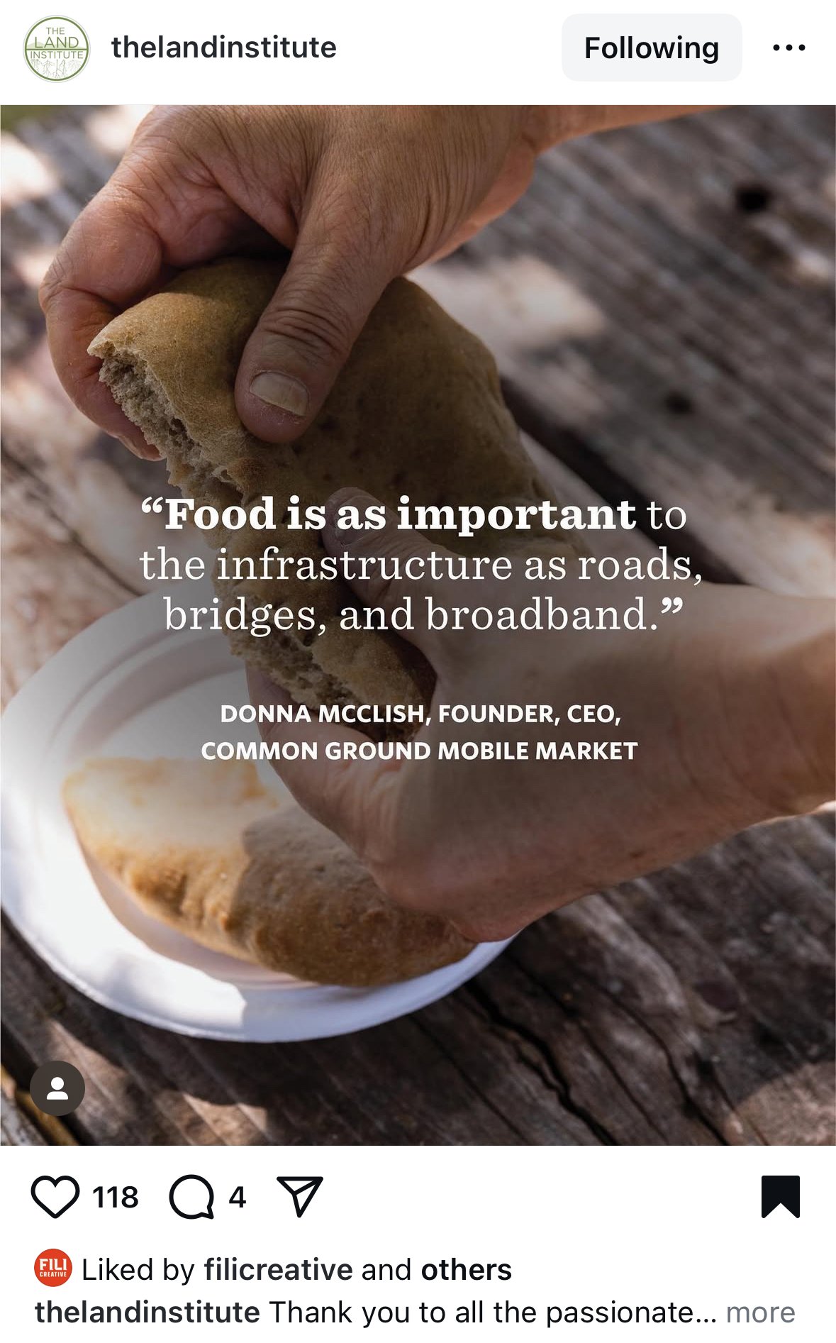 A person tearing apart a piece of bread over a paper plate on a rustic wooden surface.