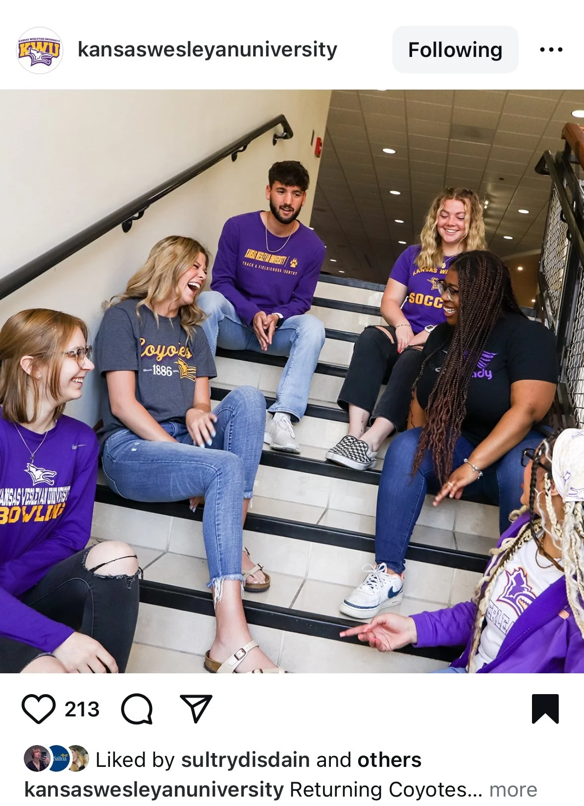 Group of young adults sitting on stairs, laughing and talking, wearing Kansas Wesleyan University apparel.