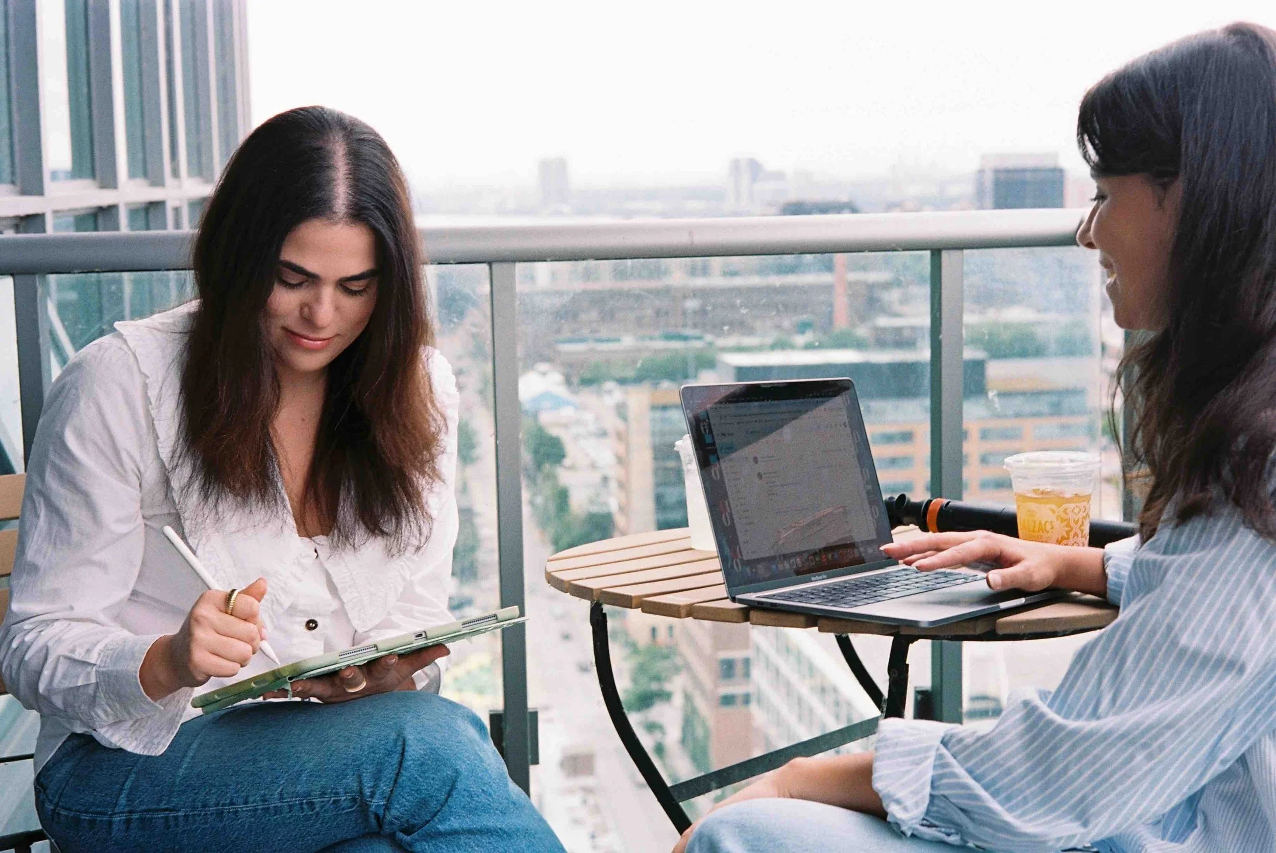 Woman with tablet and laptop planning strategic content creation with Toronto skyline in the background