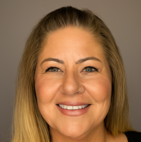 Close-up of a smiling woman with blonde hair and a nose piercing against a neutral background.