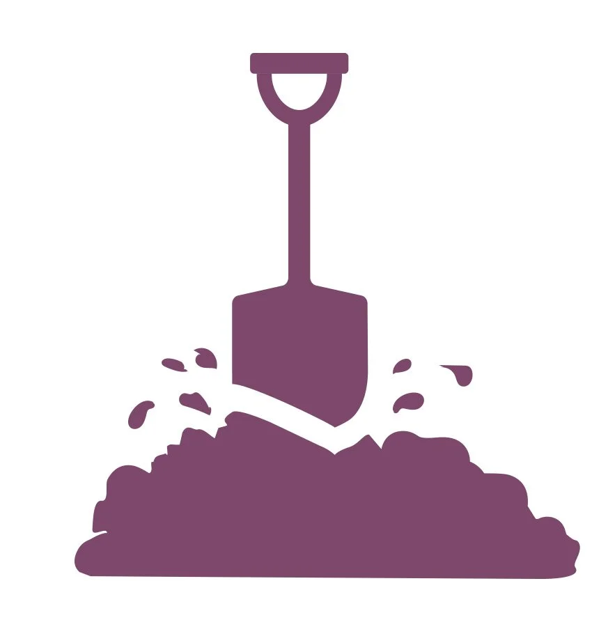 Silhouette of a shovel digging into dirt with soil and small debris flying around.
