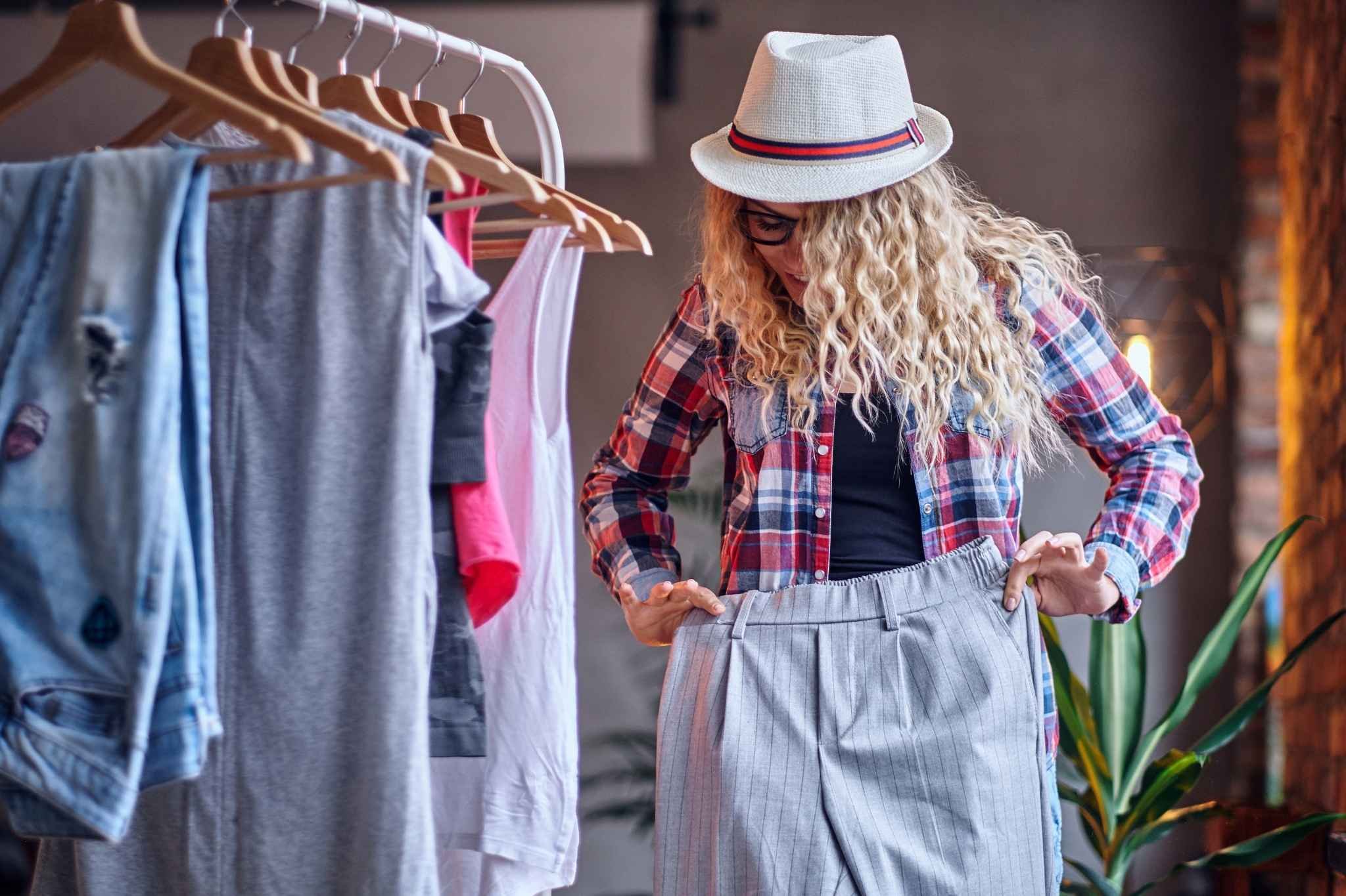 Frau probiert eine Hose an und lächelt dabei – Symbol für Freude am Kleidertauschen und bewussten Umgang mit Kleidung.