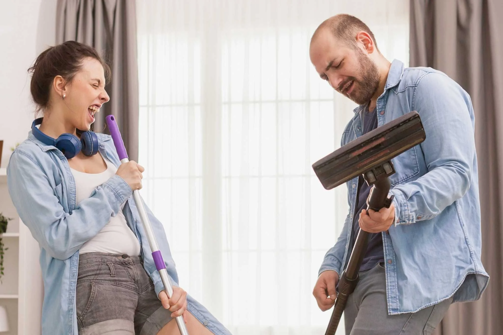 Zwei Menschen tanzen und lachen beim Aufräumen – Symbol für Leichtigkeit und Freude im Alltag.