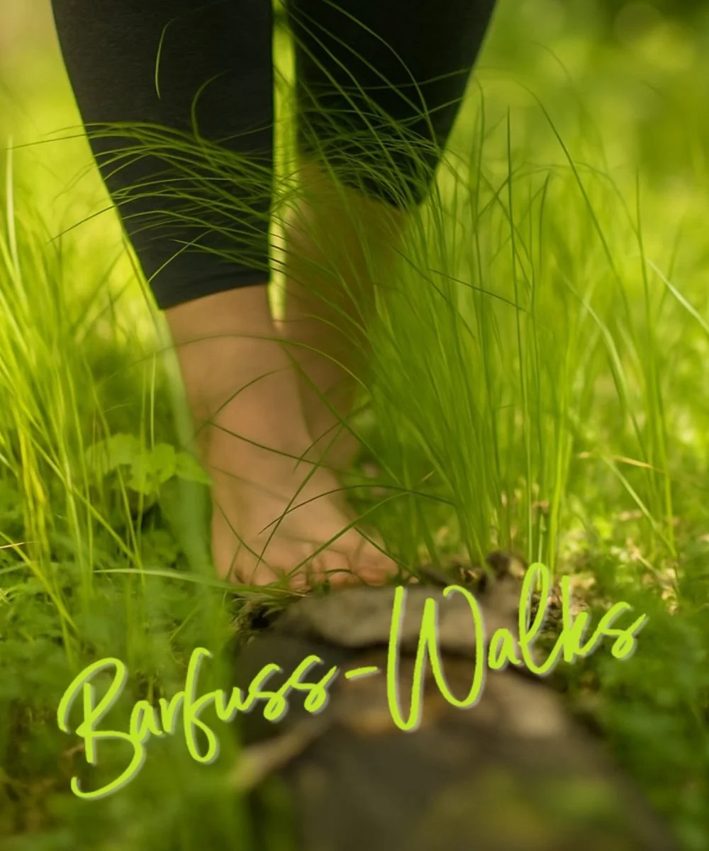 Barfuss laufende Person auf einem Naturweg, umgeben von frischem, grünem Gras. Schriftzug: "Barfuss-Walks".