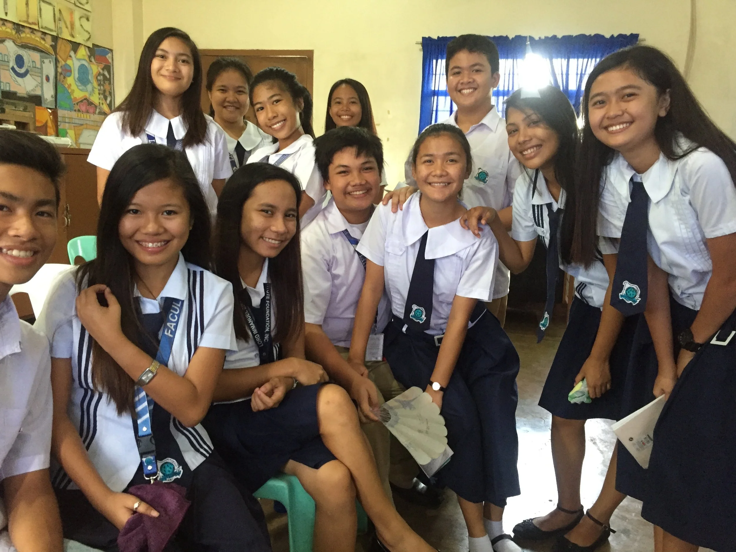 Group of diverse students in school uniforms smiling and gathered together in a classroom.