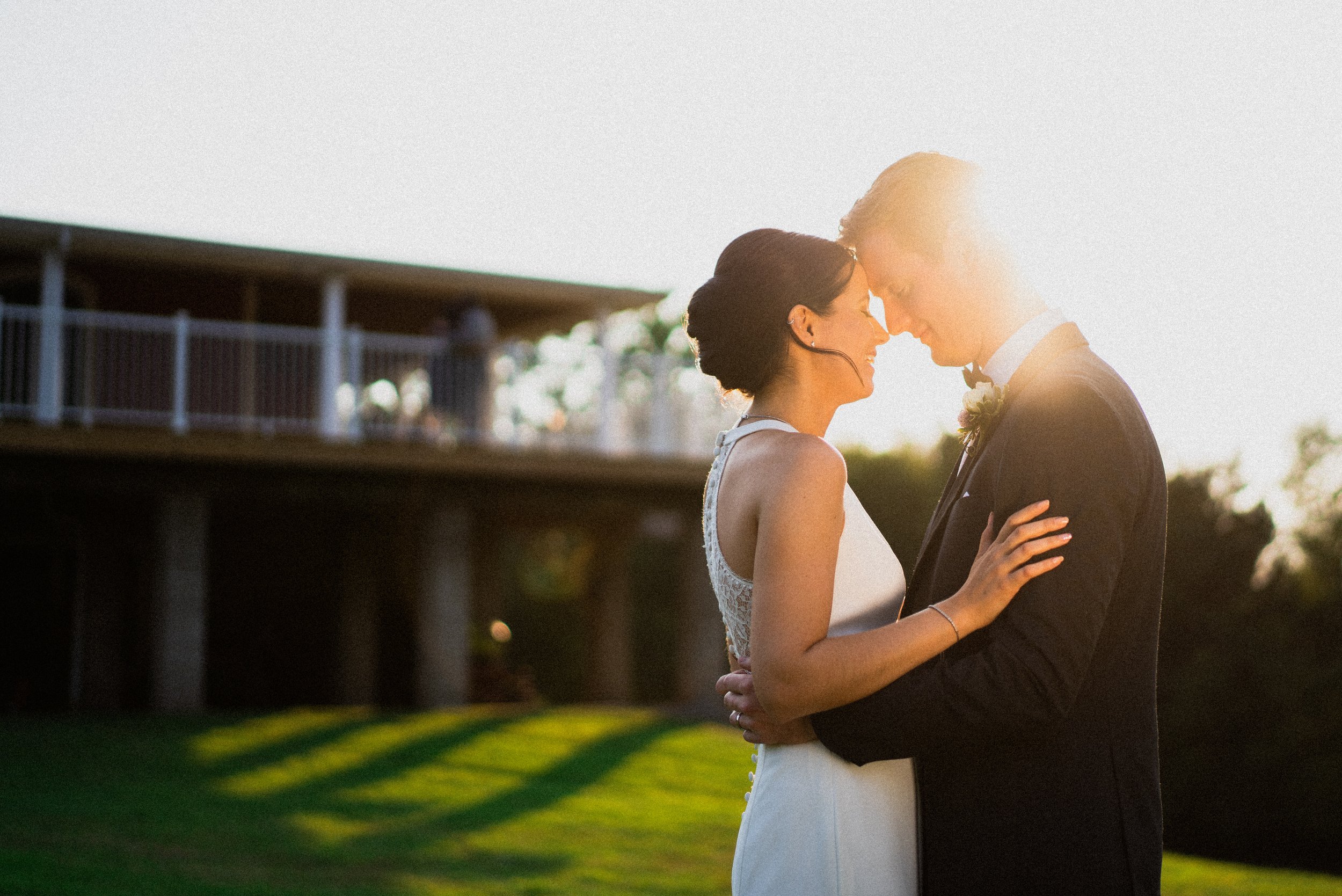 A bride and groom embrace joyfully in front of a charming house, celebrating their love on their wedding day.