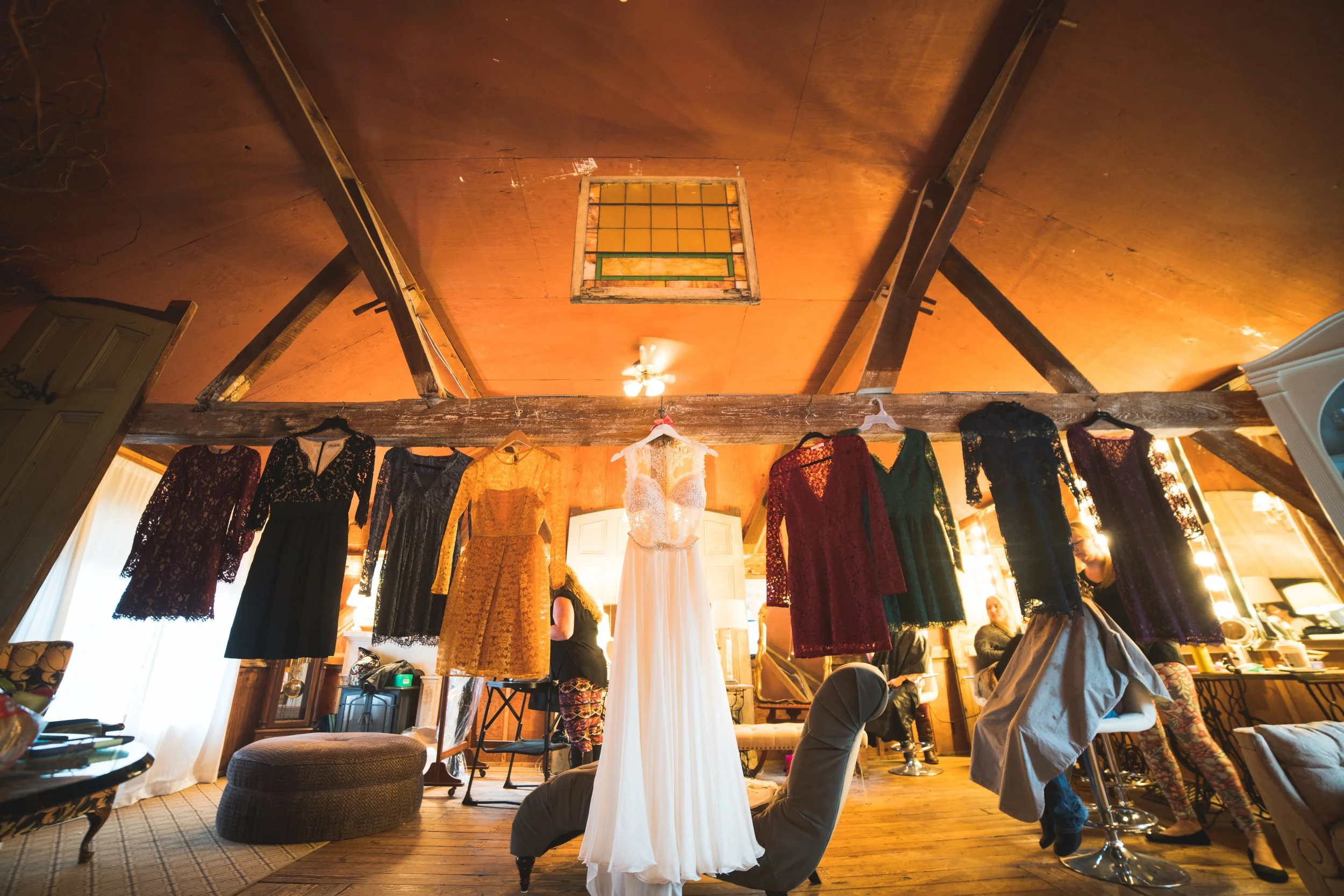 A collection of wedding dresses is displayed in a room featuring a warm wooden ceiling, enhancing the romantic setting.