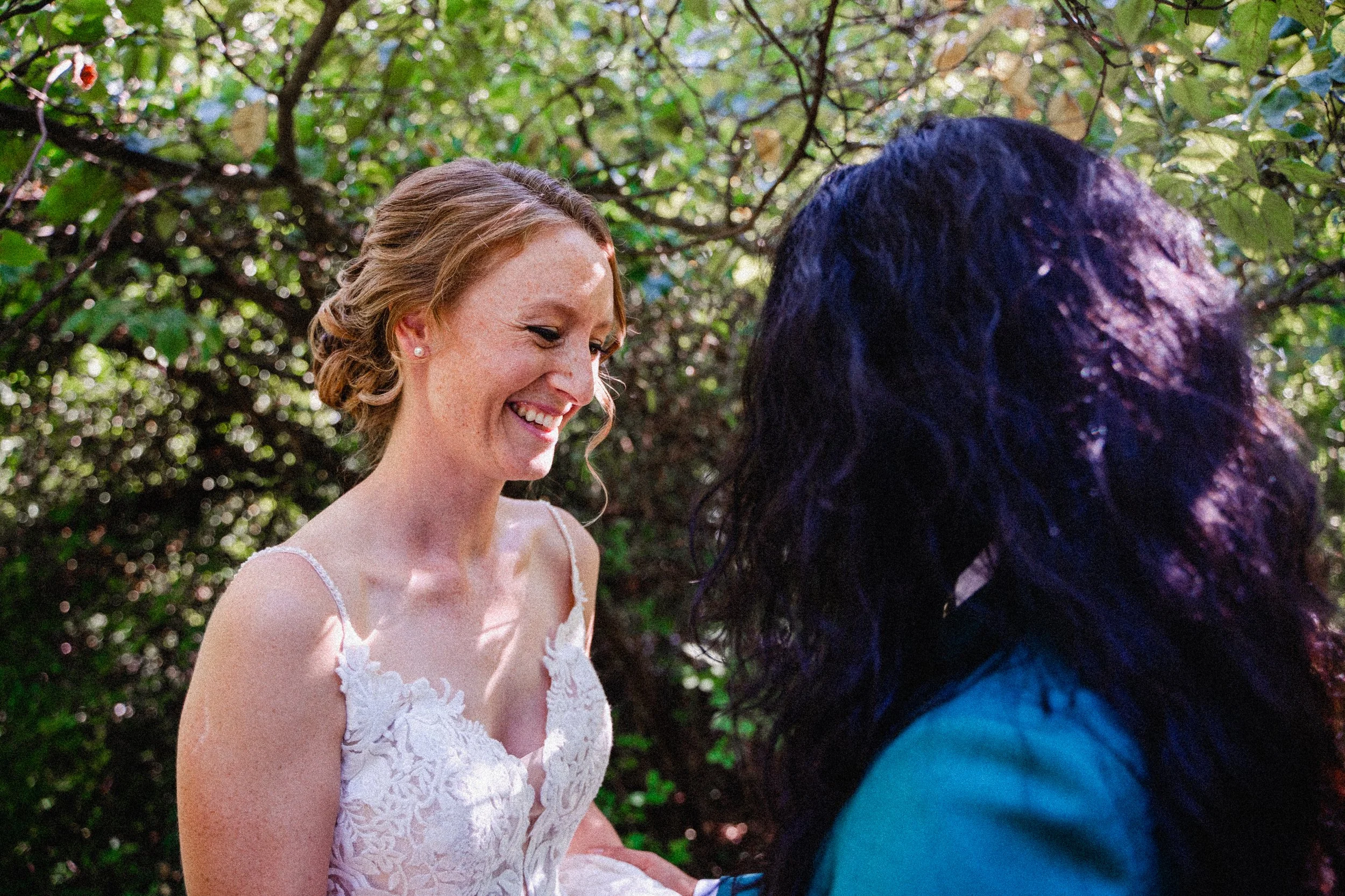 A bride and groom smile joyfully together in a serene wooded setting, surrounded by lush greenery.