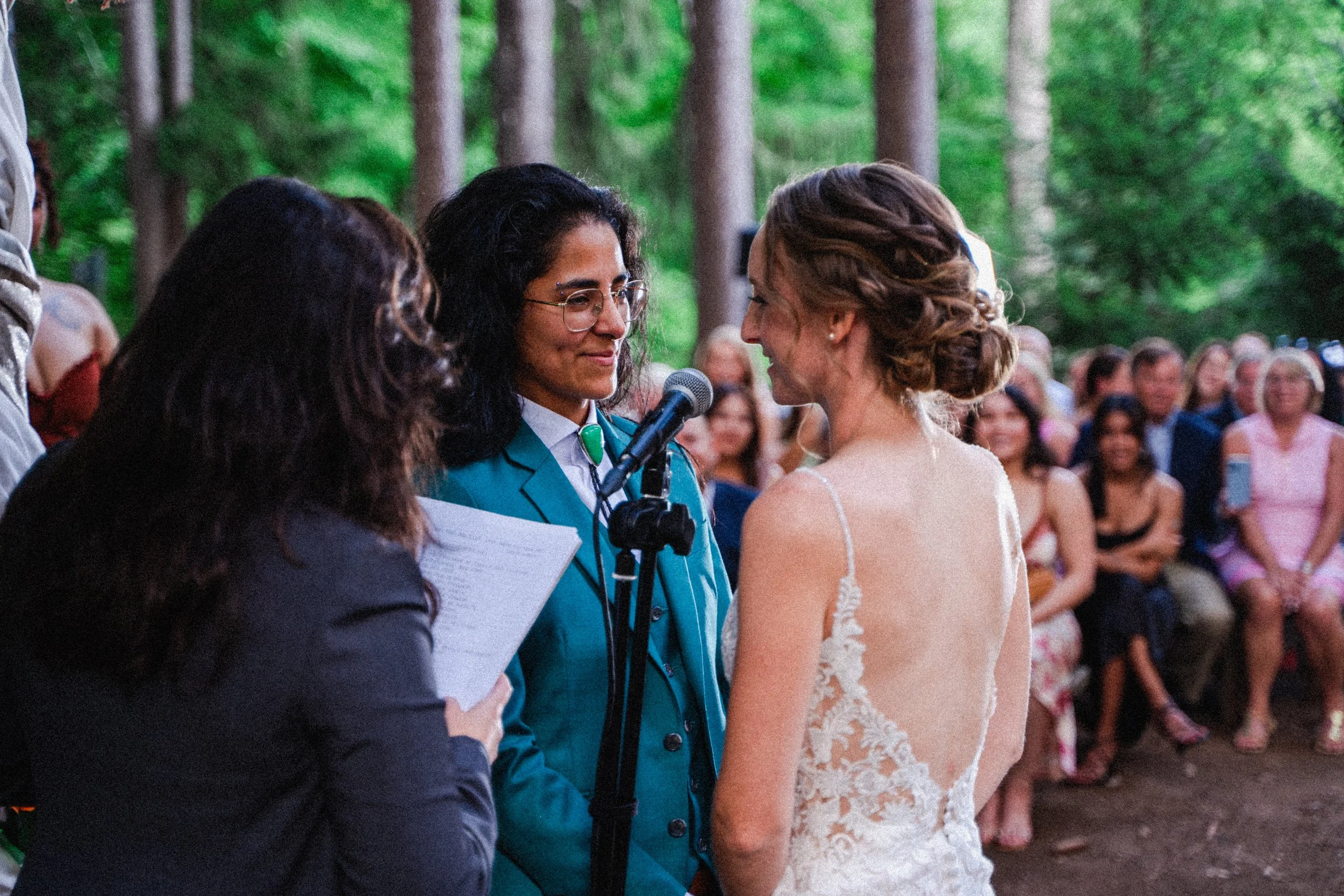 A bride and groom exchange vows during a heartfelt wedding ceremony, surrounded by floral decorations and guests.
