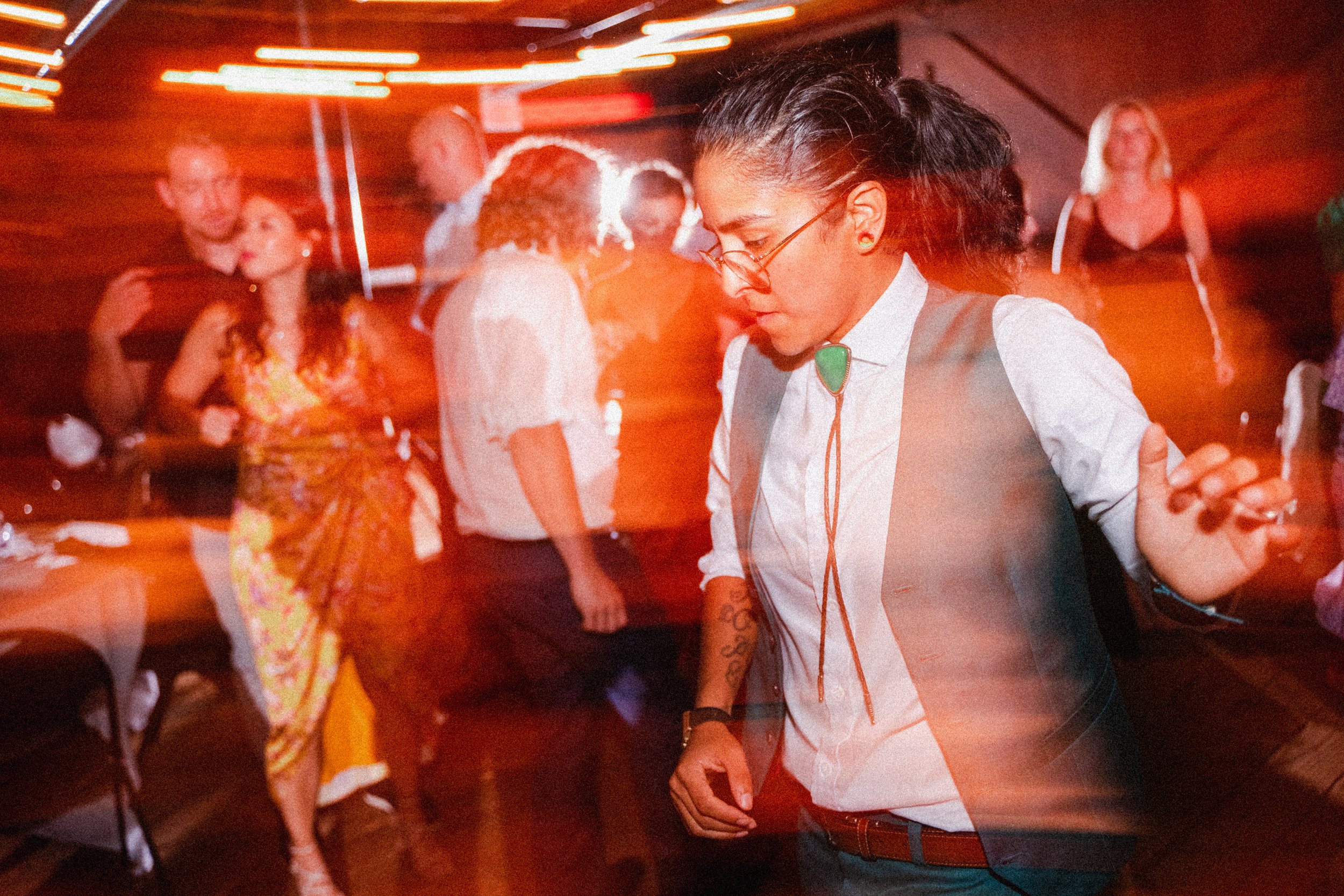 A woman joyfully dancing at a lively party, with other guests enjoying the celebration in the background.