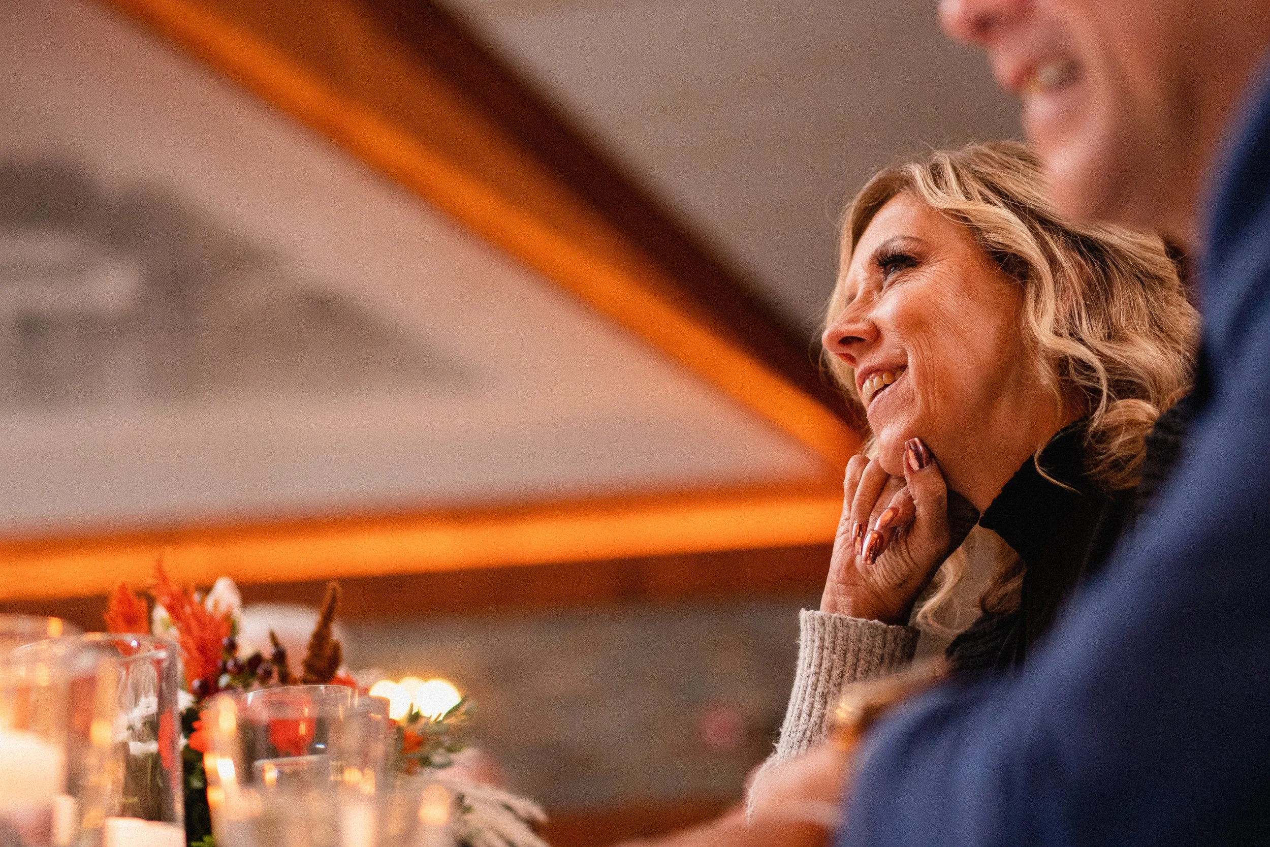 A woman smiling at a table with a man, both engaged in a pleasant conversation.