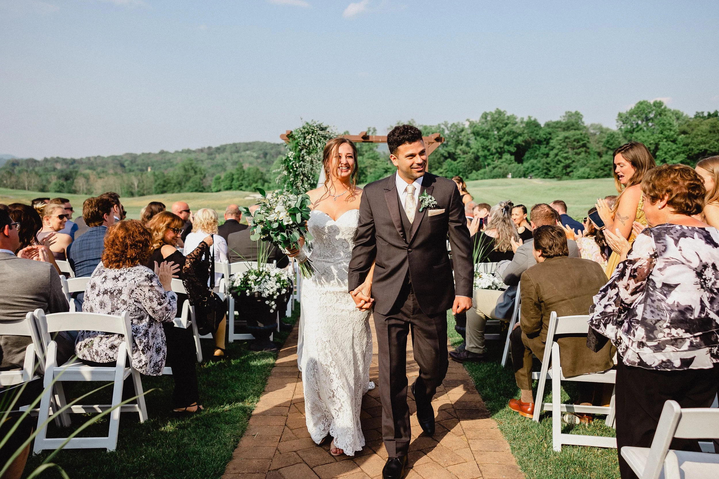 A wedding ceremony taking place outdoors at a golf club, with guests seated and a decorated altar in the background.