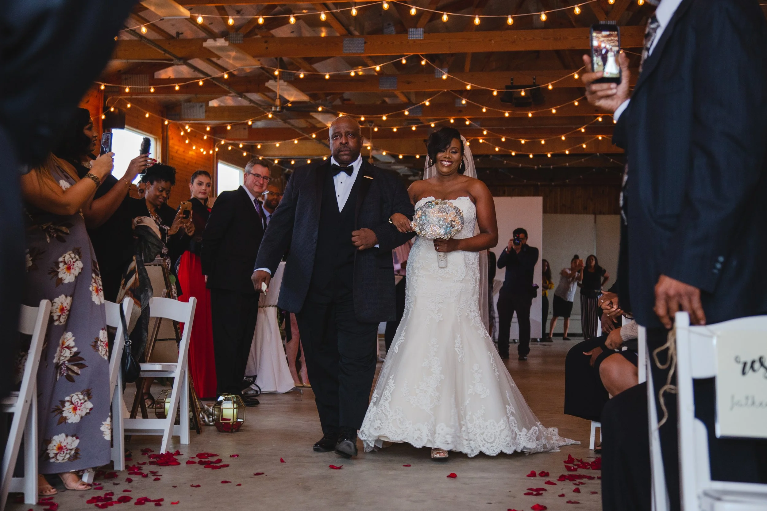 A rustic wedding ceremony taking place inside a charming barn on a farm, decorated with flowers and soft lighting.
