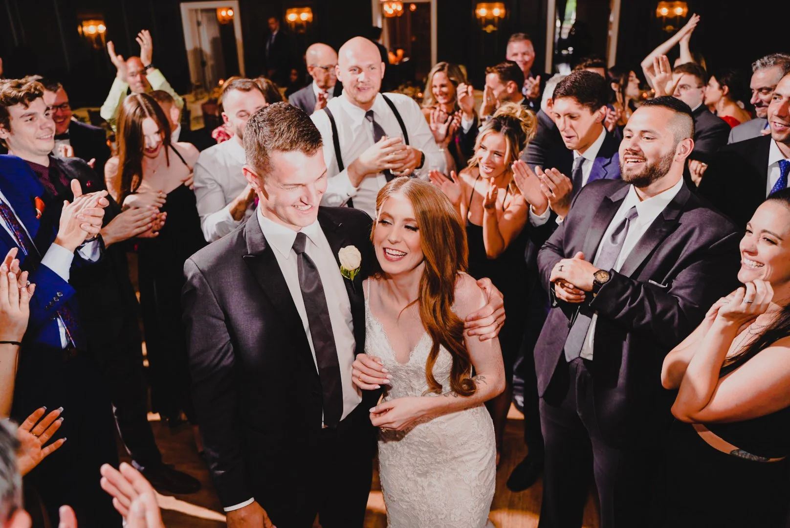 A bride and groom celebrate their wedding reception, surrounded by joyful guests in a festive atmosphere.