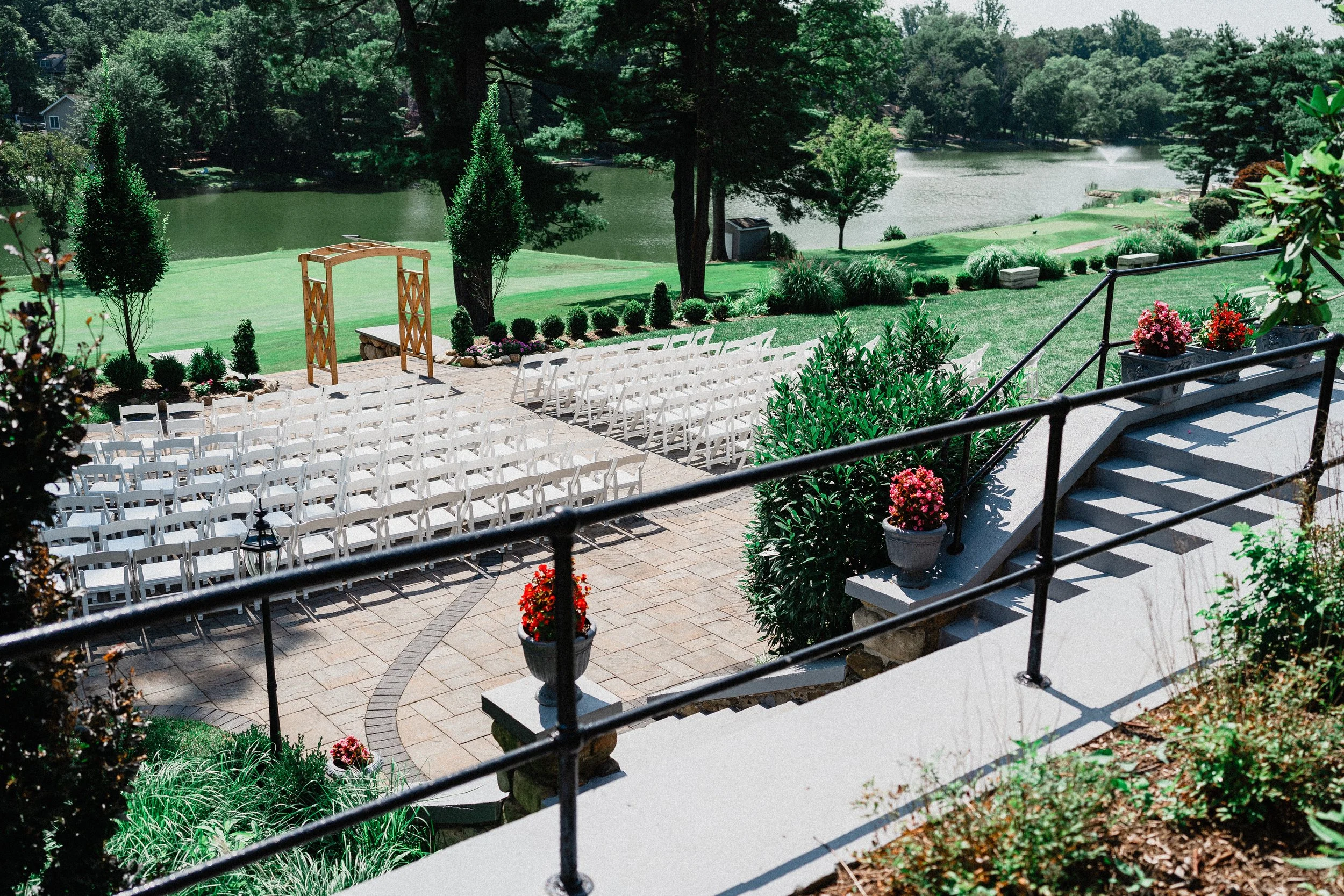 Outdoor wedding ceremony by a serene lake, with guests seated and a floral arch framing the couple exchanging vows.