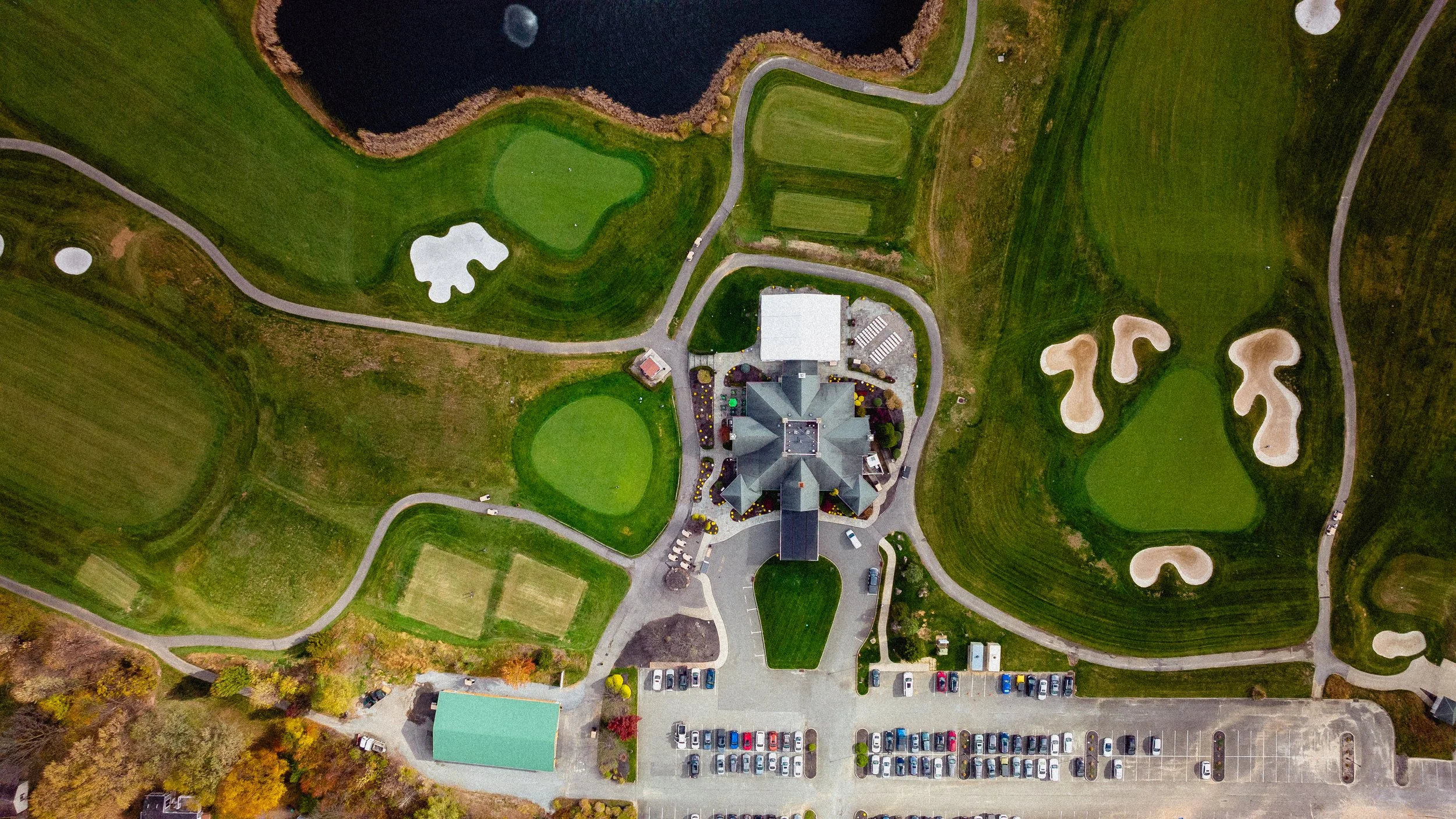 Aerial view of a lush golf course featuring a serene pond surrounded by green fairways and trees.