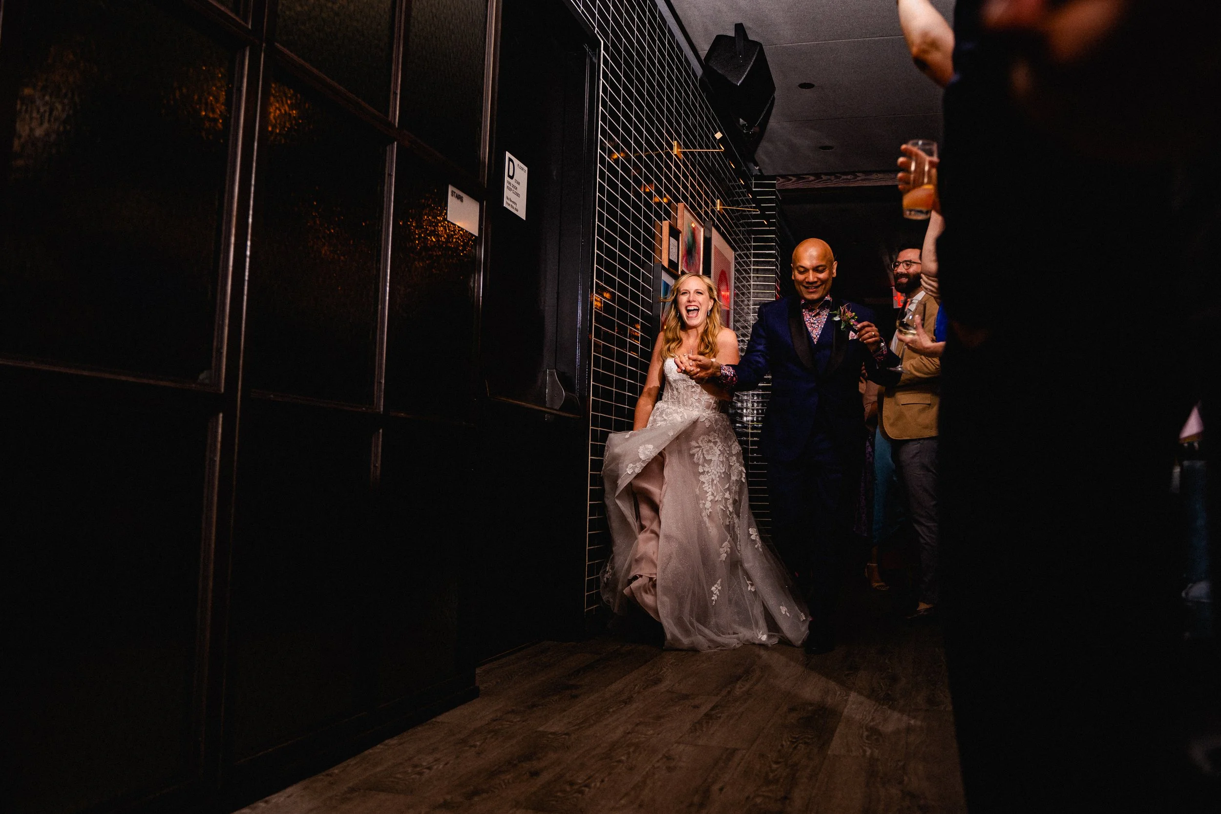Bride and groom joyfully walking down the aisle, surrounded by floral decorations and smiling guests.