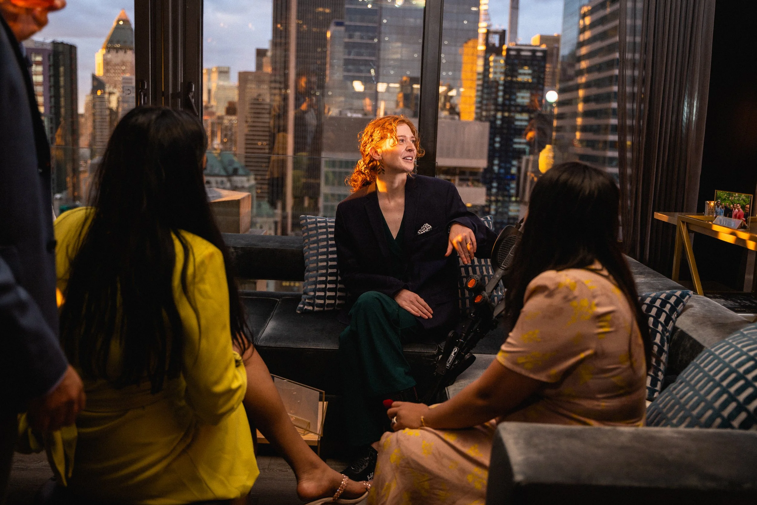 A woman seated in a chair surrounded by several people engaged in conversation.