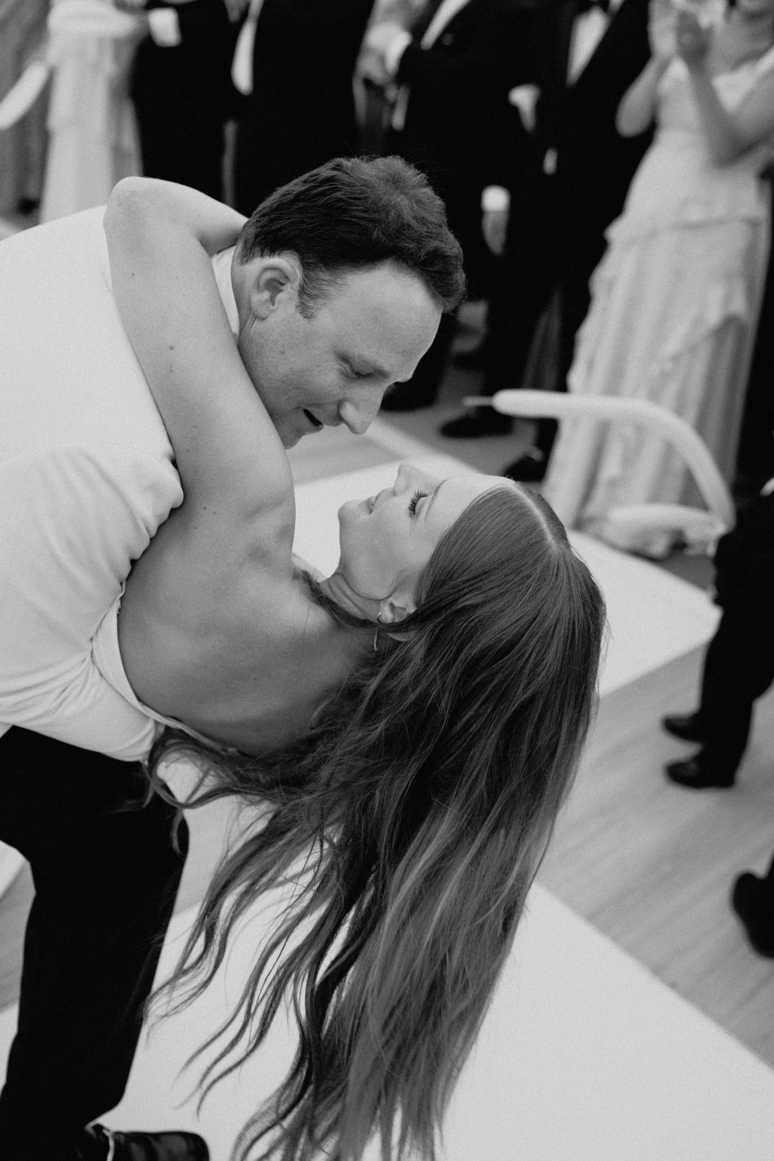 Documentary wedding photography close-up of newlyweds kissing during a lively tented reception in Upstate New York.