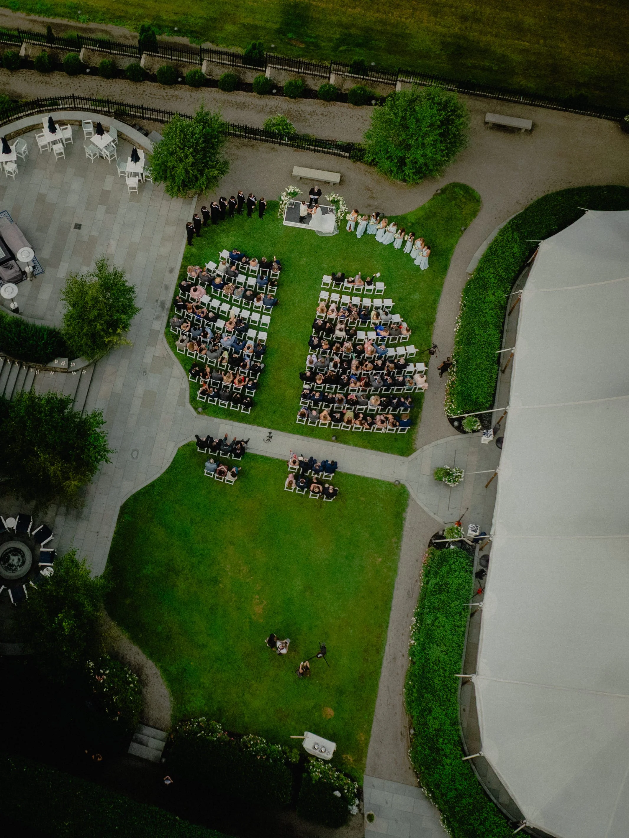Luxury wedding photography aerial view of an outdoor ceremony on an Upstate New York estate lawn beside a tent.
