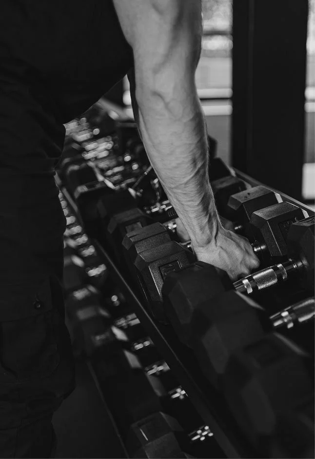 A person lifting a dumbbell in a gym, focusing on their arm and the weight.